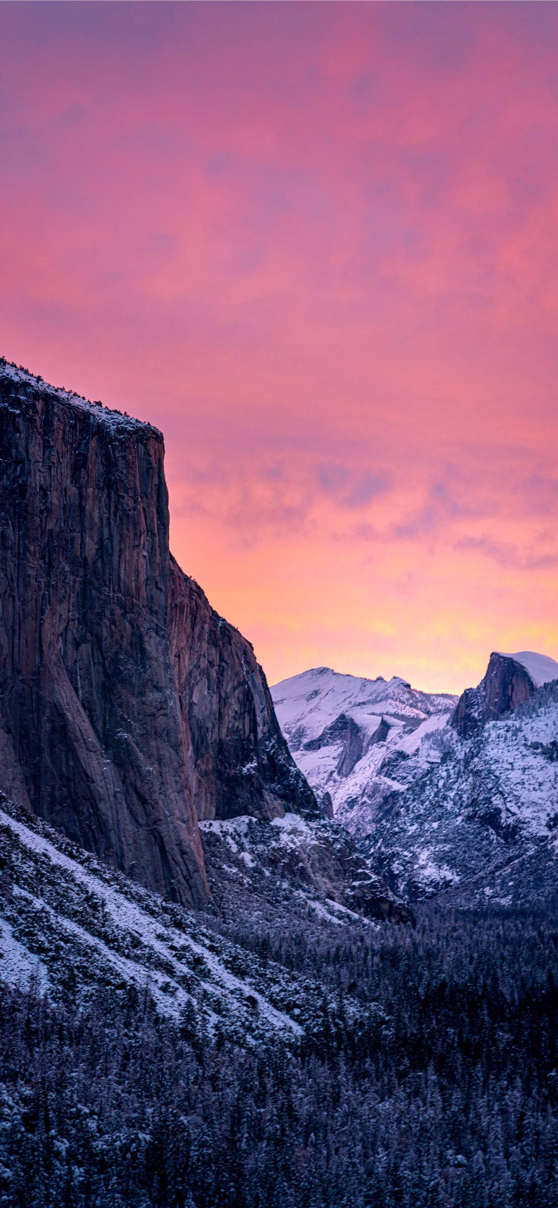 Yosemite iPhone 桌布 壁紙 — 日落時分，白雪覆蓋的山谷，崎嶇的懸崖和常綠樹上方呈現粉紅色和紫色的天空。