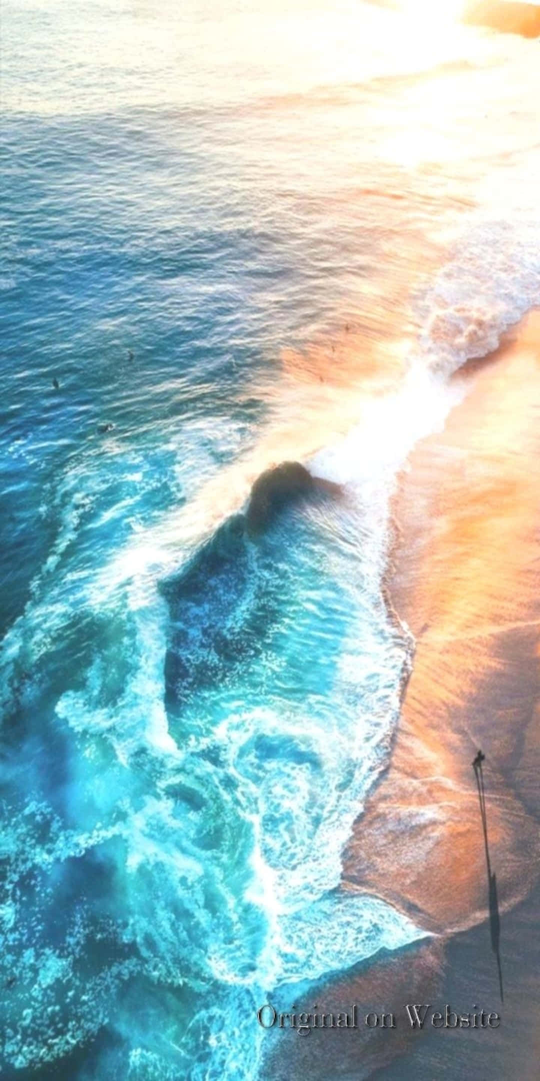 Pixel 3 Beach 桌布 壁紙 — 日落時分，綠松石色的海浪拍打金色沙灘，衝浪者乘風破浪的鳥瞰圖。
