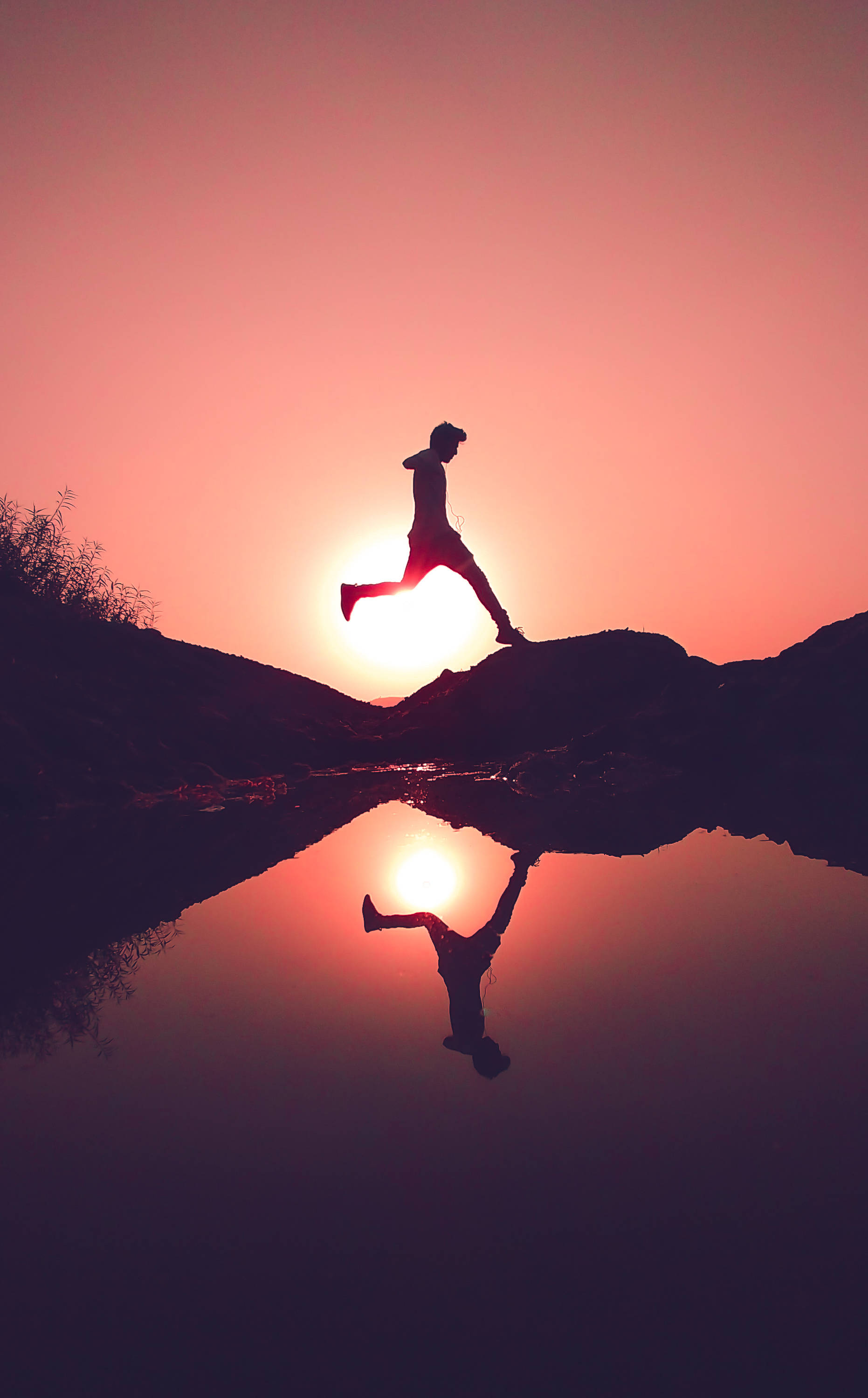 Parkour 桌布 壁紙 — 日落時分，跑者躍過岩石的剪影，在平靜水面上完美倒映。