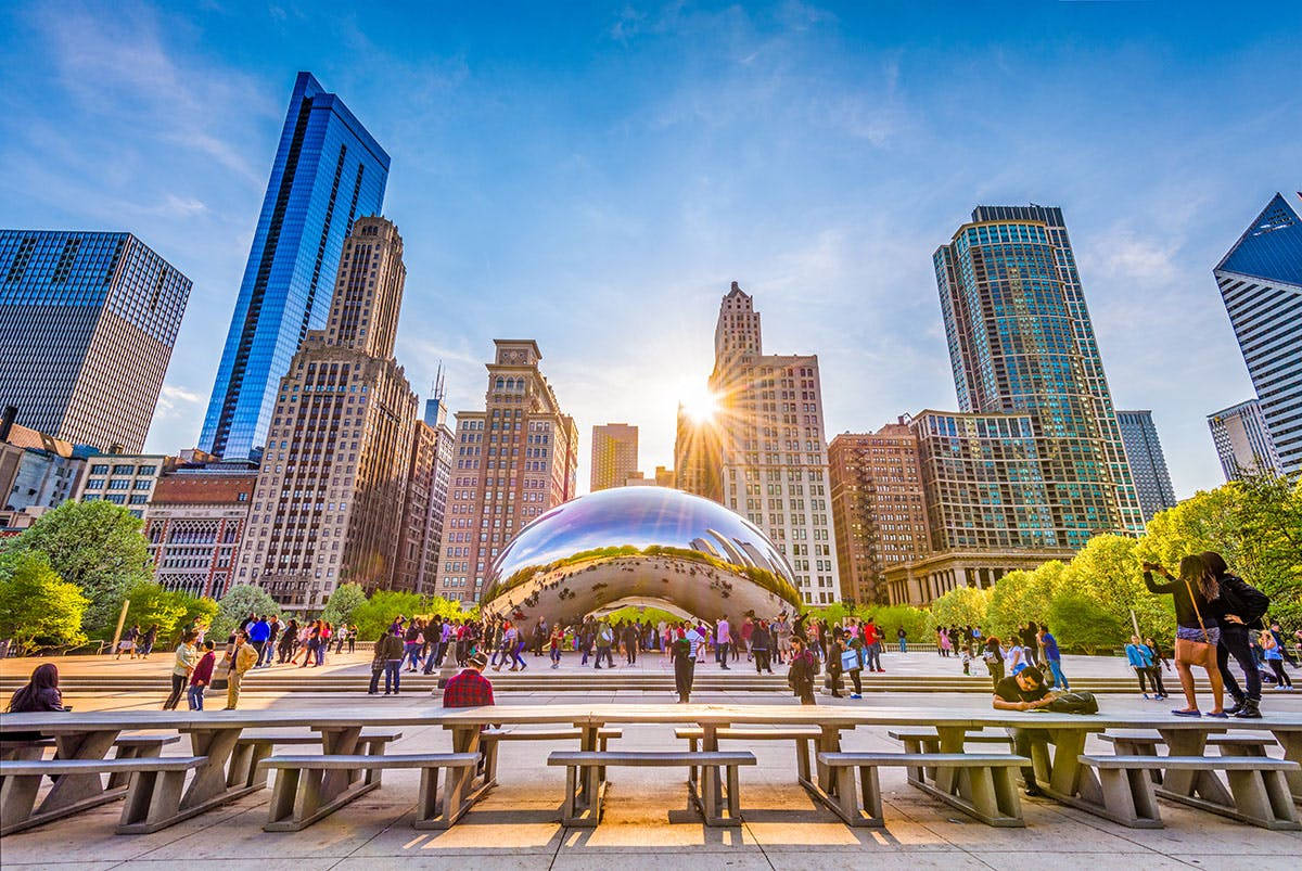 Skyscraper 桌布 壁紙 — 日落時分充滿活力的城市景觀， featuring 反射性的 Cloud Gate 雕塑，周圍有人群和現代摩天大樓。