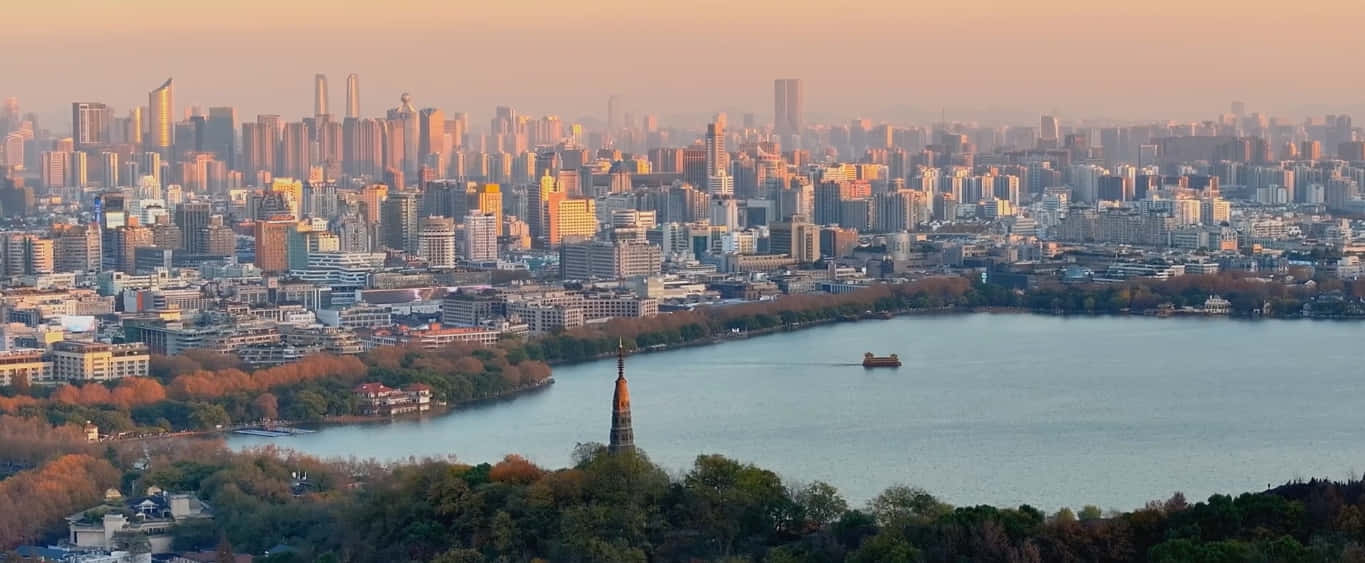 Panorama 桌布 壁紙 — 日落時分城市天際線的全景，前景有一個大湖，一艘船在水面上滑行。