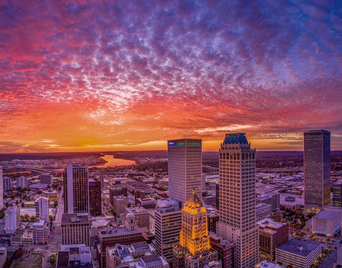 Oklahoma 桌布 壁紙 — 日落時分城市天際線的鳥瞰圖，高聳的摩天大樓上方有火熱的橙色和紫色雲彩，下方是發光的河流。