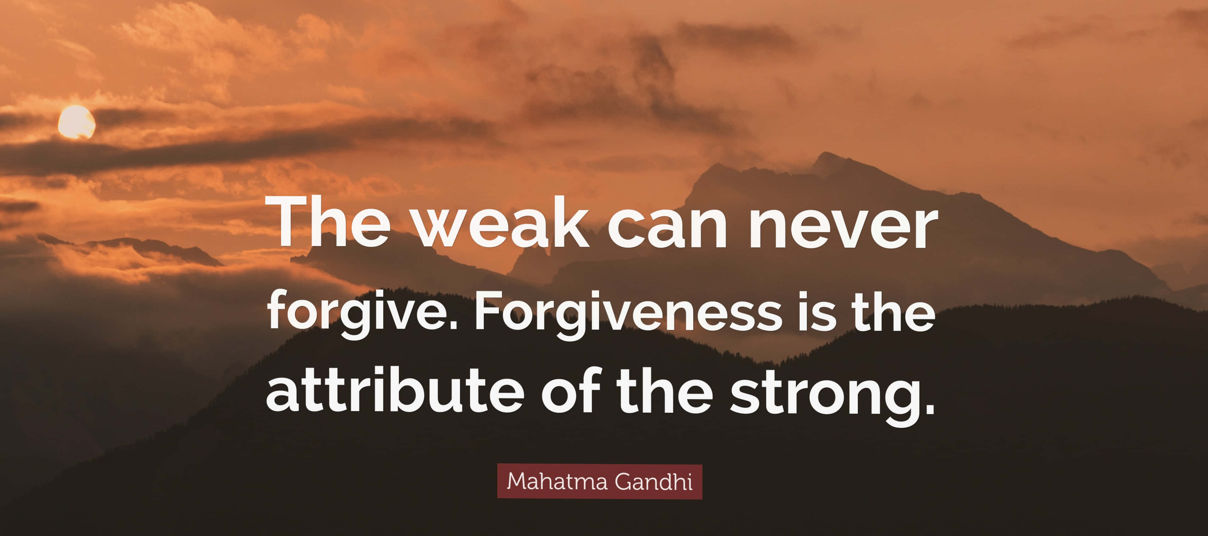 Forgiveness 桌布 壁紙 — 日落時分寧靜的山脈輪廓，伴隨著溫暖的橙色雲彩，並疊加了聖雄甘地的名言。