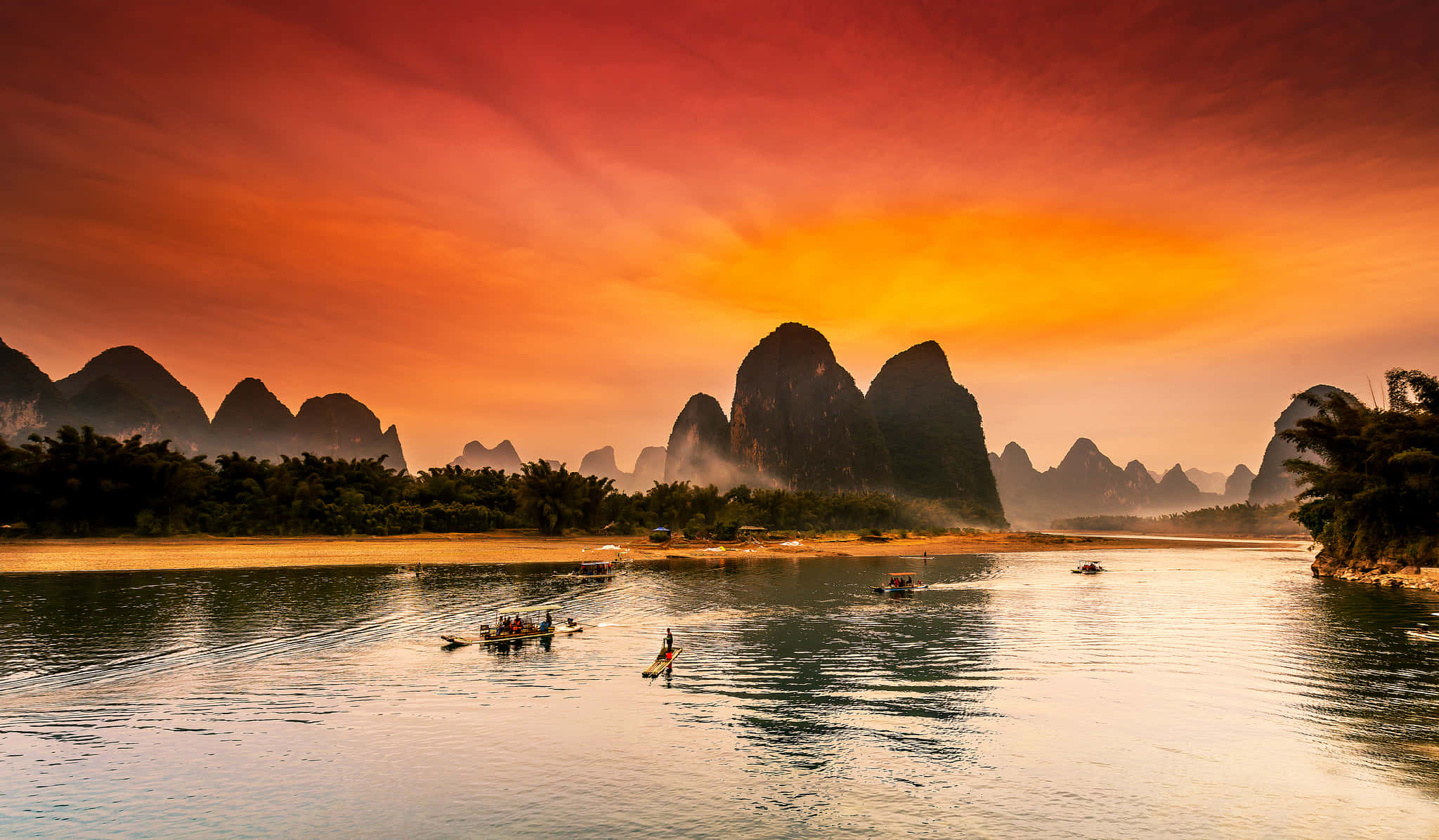 Landscapes 桌布 壁紙 — 日落時分寧靜的河流，喀斯特山脈倒映在平靜的水面上，小船在迷霧中輕輕滑過。