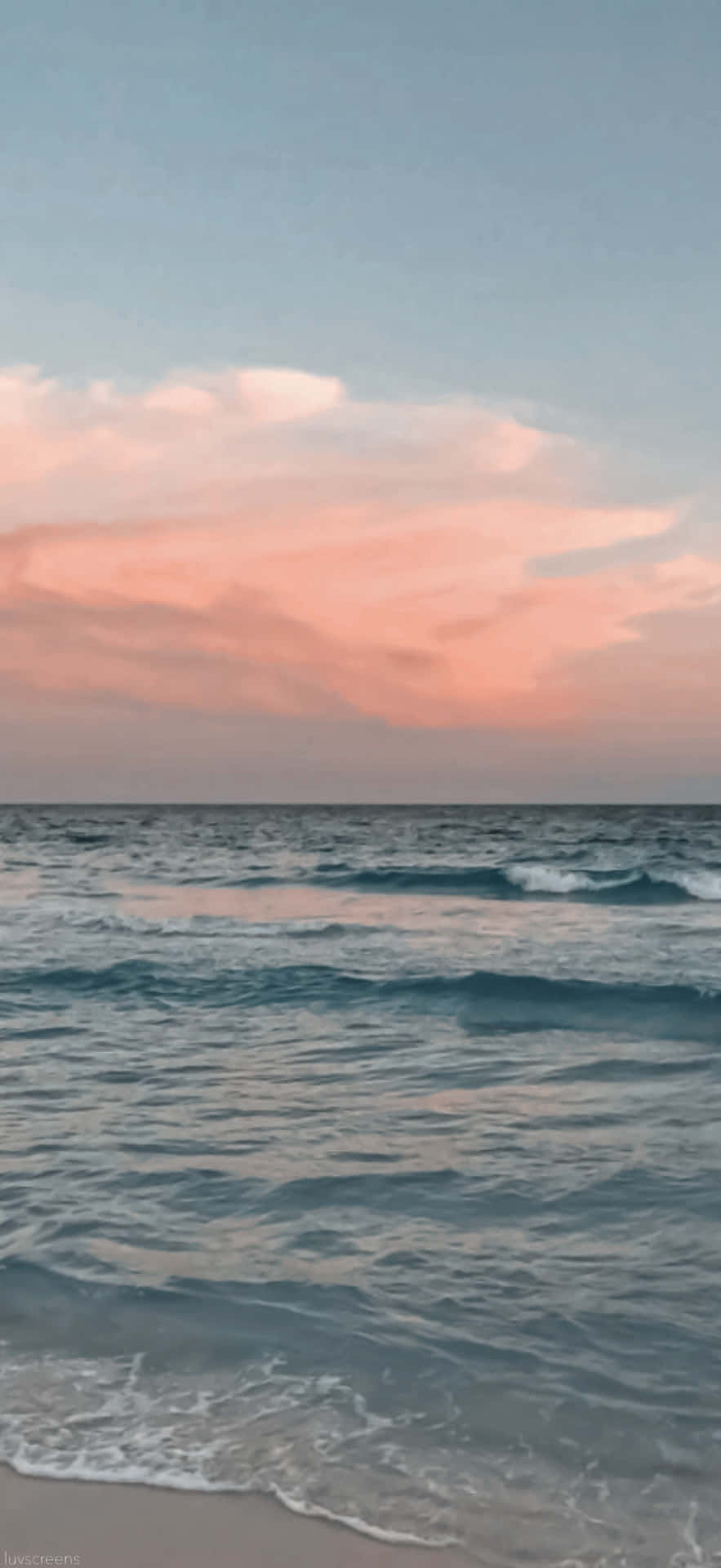 Beach Aesthetic Tumblr 桌布 壁紙 — 日落時分寧靜的海洋，柔和的粉紅雲彩映照在輕柔的海浪上，緩緩湧上沙灘。