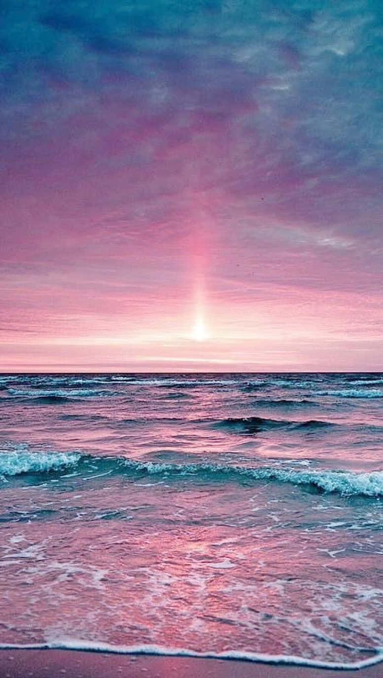 Cute Beach iPhone 桌布 壁紙 — 日落時分寧靜的海洋，粉紅色和紫色的雲彩映照在溫柔的波浪上。