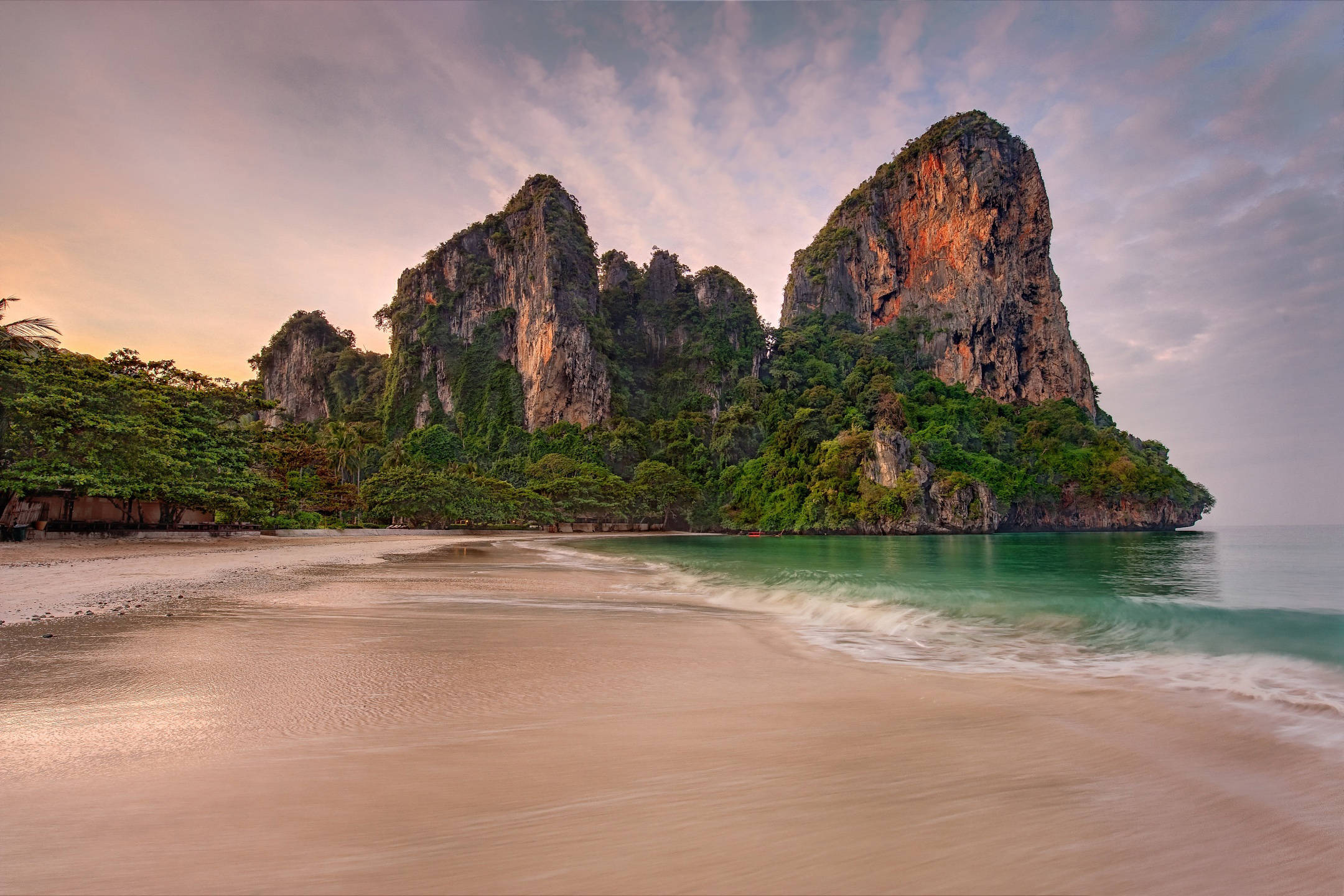 Sea 桌布 壁紙 — 日落時分寧靜的熱帶海灘，碧綠的海浪拍打著金色沙灘，背景是叢林覆蓋的高聳石灰岩懸崖。