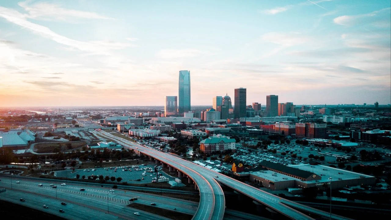 Oklahoma 桌布 壁紙 — 日落時分廣闊城市景觀的鳥瞰圖，蜿蜒的高速公路穿過城市擴張，摩天大樓在逐漸消失的光線中閃耀。