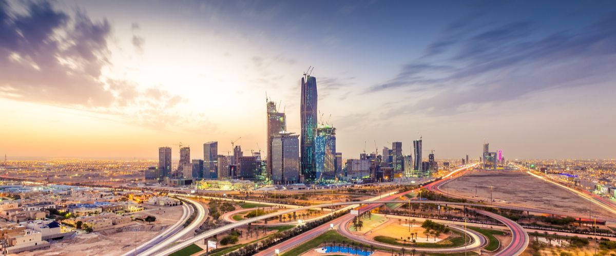 Riyadh 桌布 壁紙 — 日落時分廣闊的現代城市景觀，閃爍的摩天大樓和充滿光跡的彎曲高速公路。