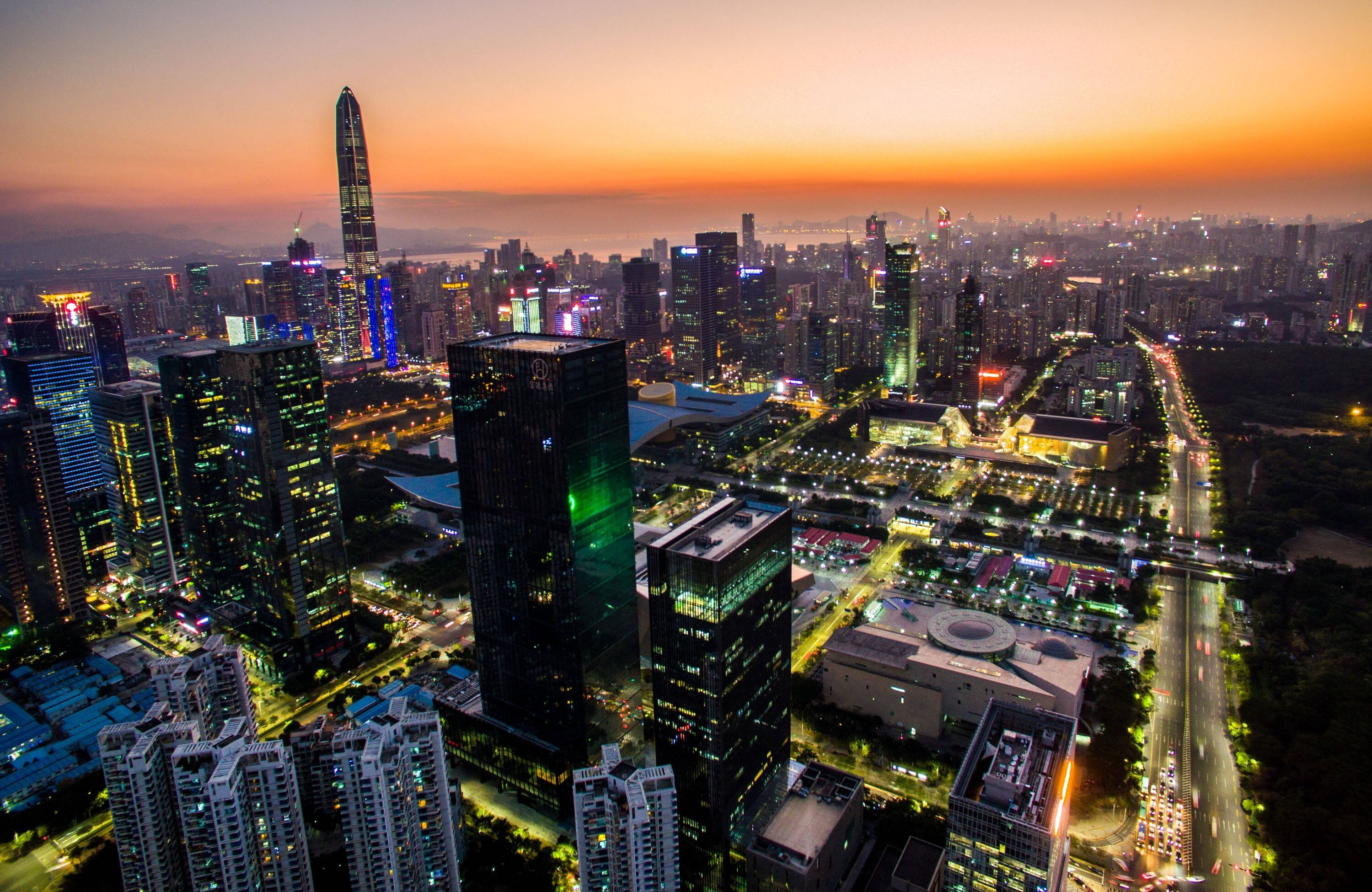 Shenzhen 桌布 壁紙 — 日落時分未來城市景觀的鳥瞰圖，閃爍的摩天大樓和燈火通明的街道。
