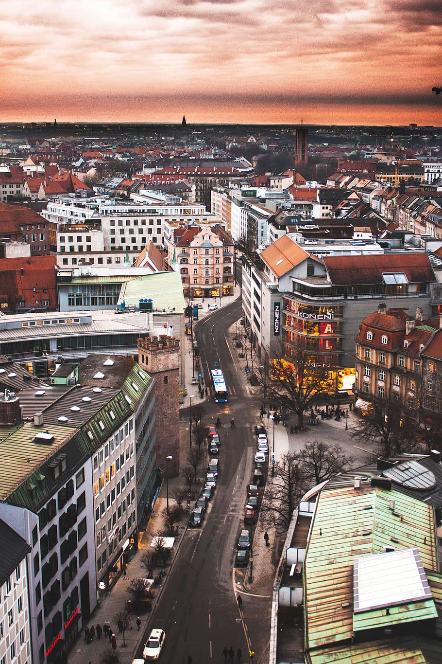 Munich 桌布 壁紙 — 日落時分歐洲城市景觀的鳥瞰圖，溫暖的橙色天空和蜿蜒街道兩旁的歷史建築。