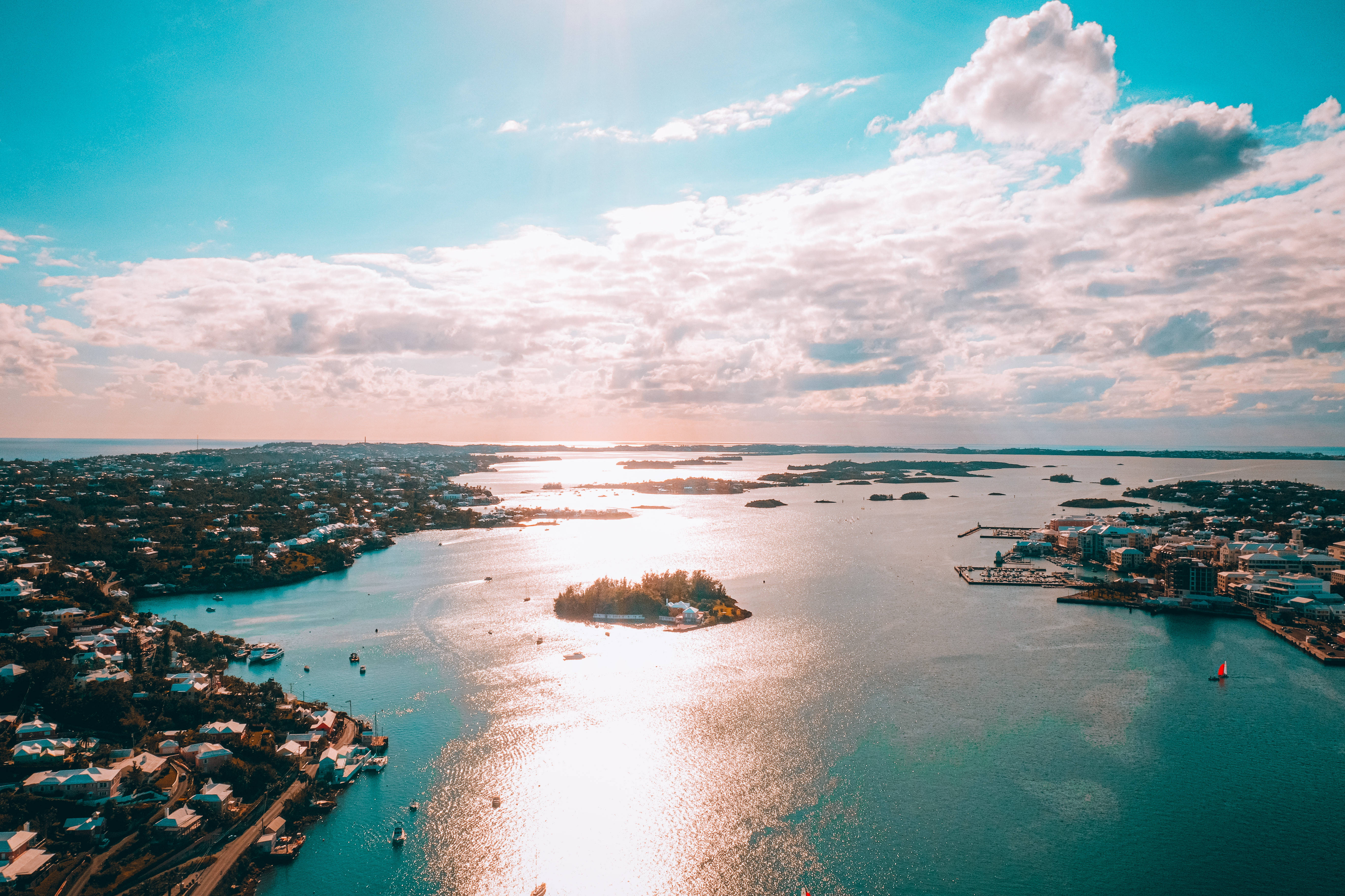 Bermuda 桌布 壁紙 — 日落時分沿海城市的鳥瞰圖，金色陽光反射在碧綠的海水和散落的島嶼上。
