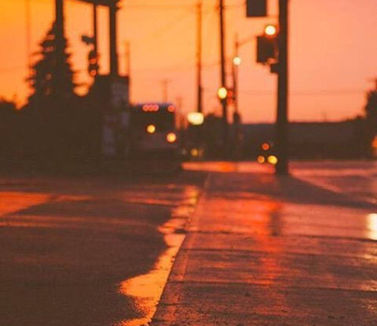 風景 桌布 壁紙 — 日落時分濕潤的城市街道反射著交通號誌燈和遠處車輛的溫暖橙色燈光。