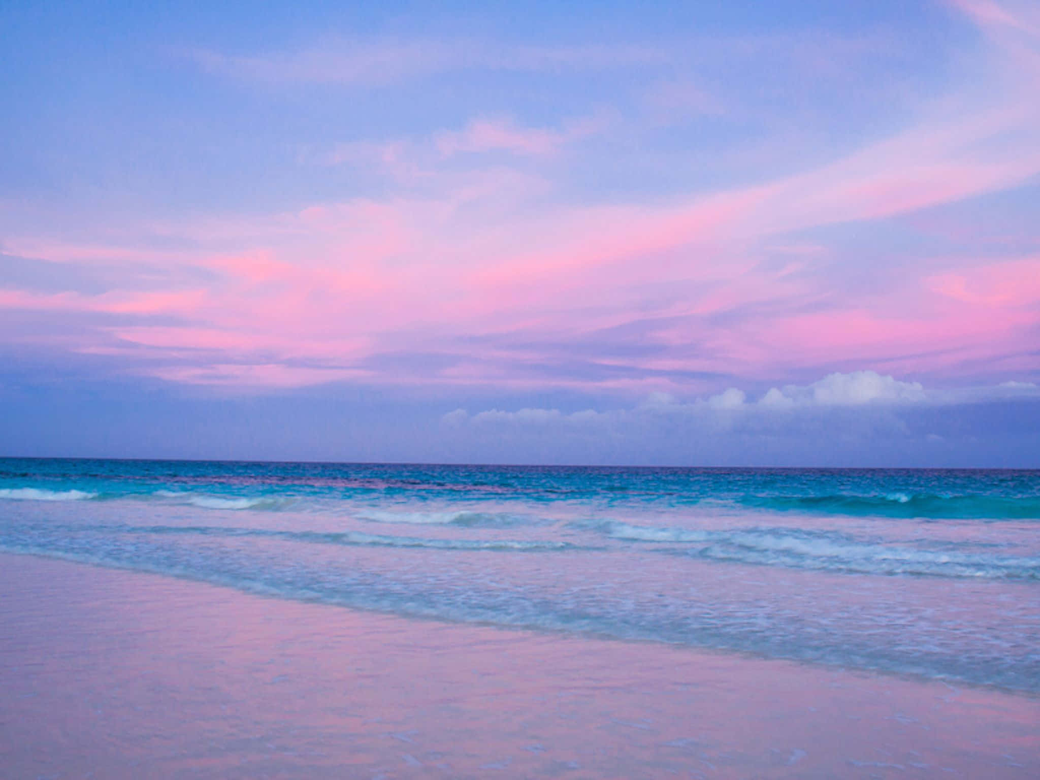 Bahamas Beach 桌布 壁紙 — 日落時分的寧靜海灘，粉紅色和紫色的雲彩倒映在碧綠的海浪和濕沙上。