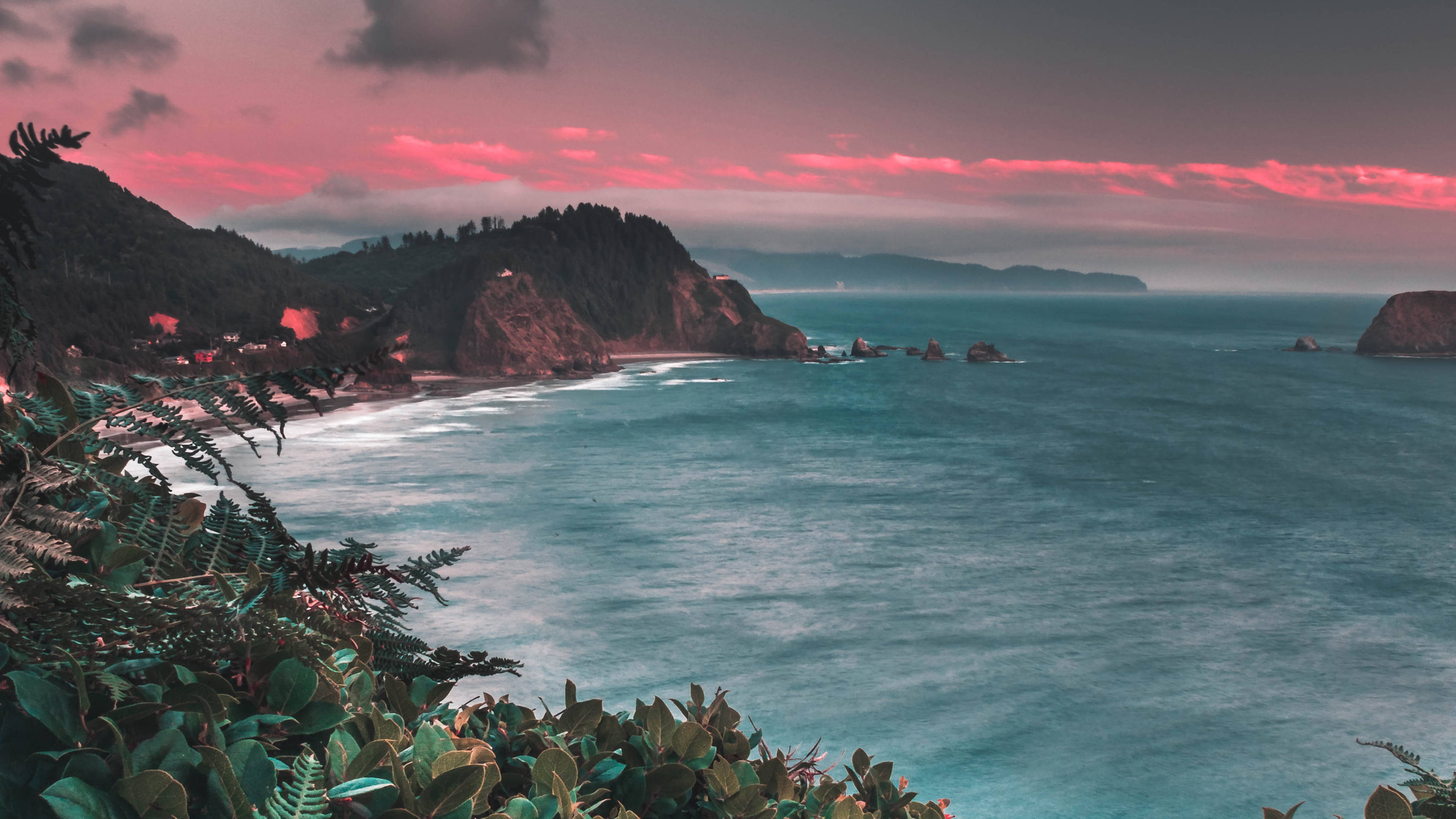 Beautiful Sea 桌布 壁紙 — 日落時分的戲劇性海岸景色，粉紅色的雲彩在碧綠的海水和茂密的綠色懸崖之上。