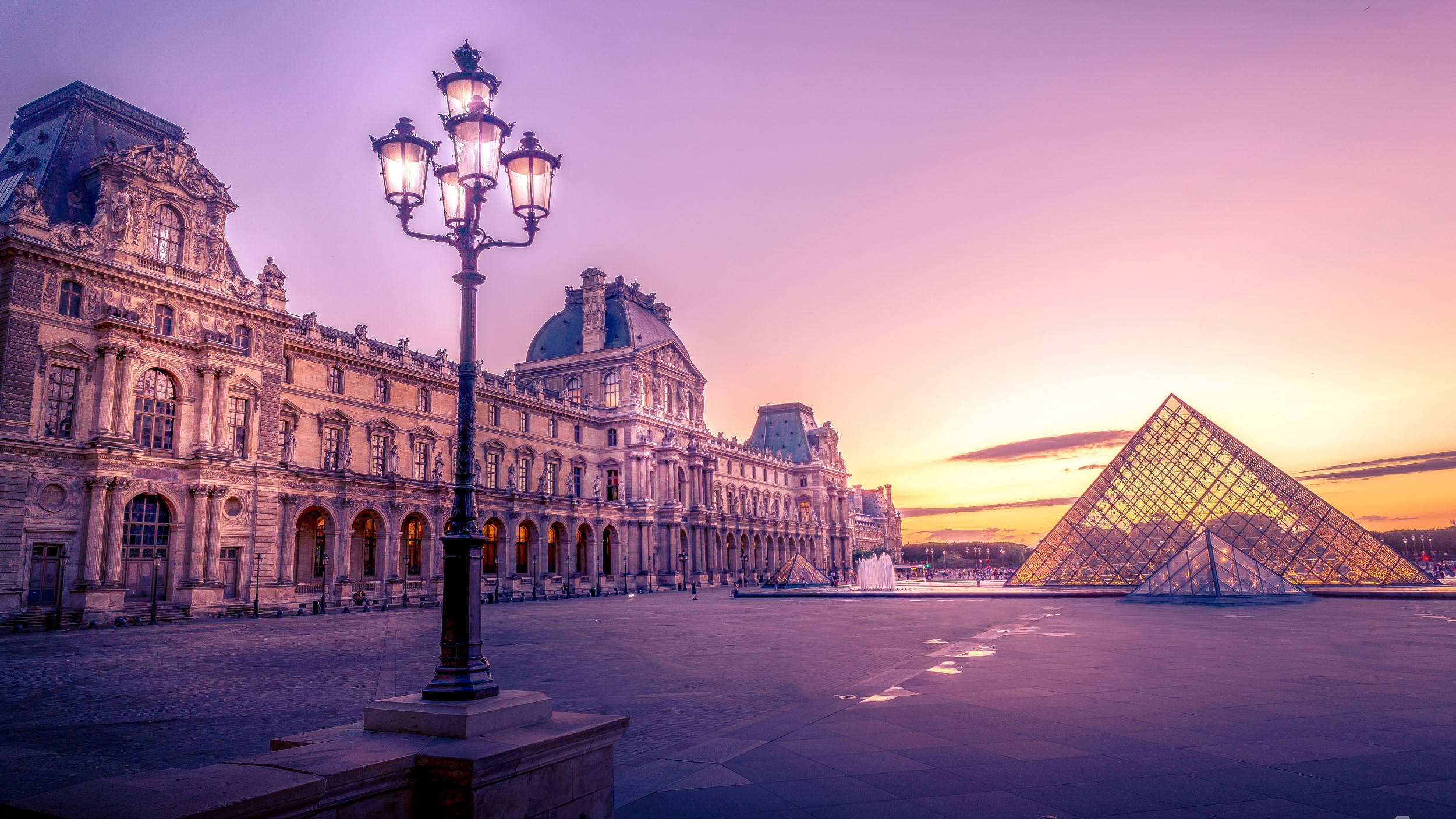 France 桌布 壁紙 — 日落時分的羅浮宮，其標誌性的玻璃金字塔在紫色和橙色的天空下閃耀。