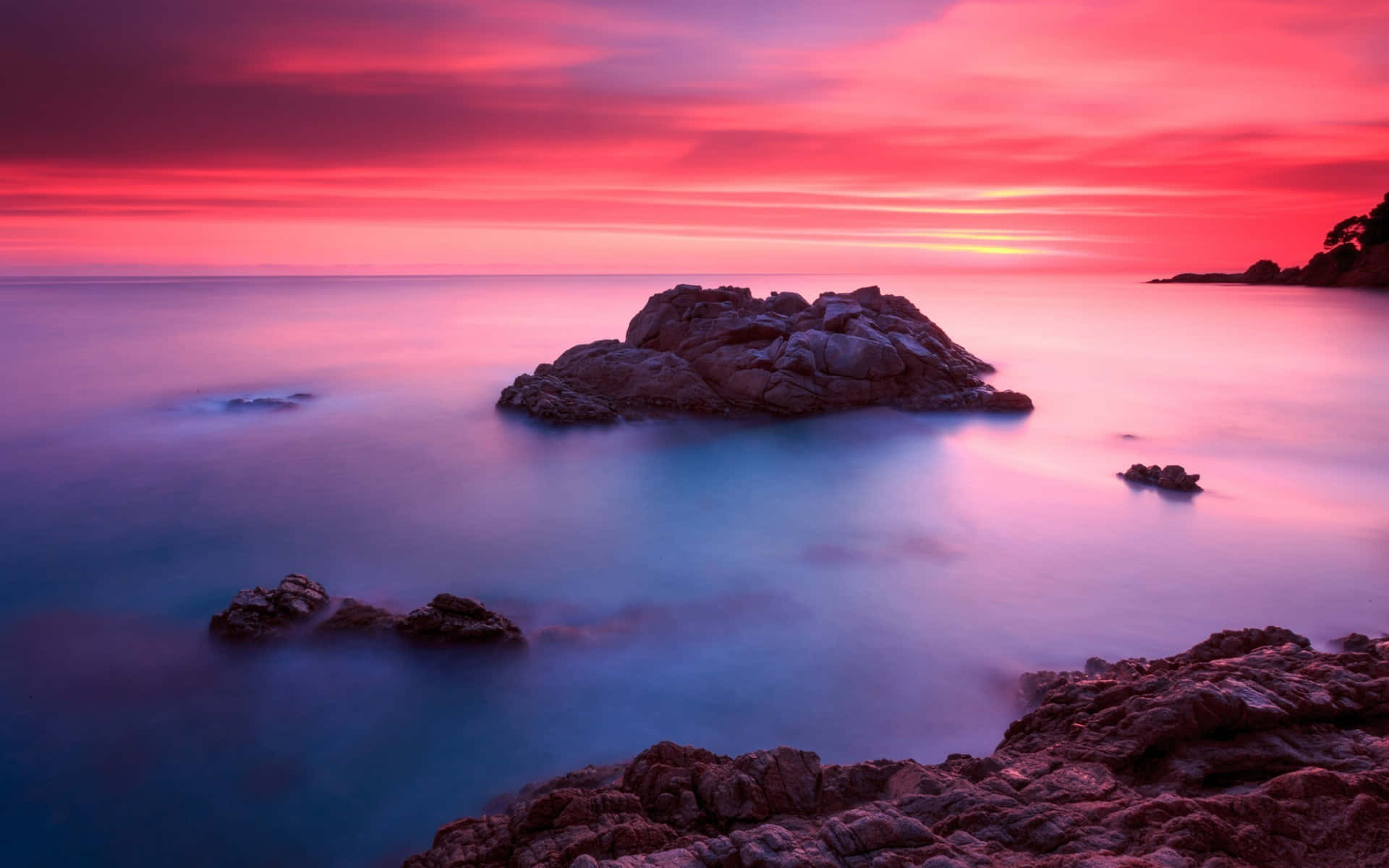 Photography Nature 桌布 壁紙 — 日落時分的長時間曝光海景，鮮豔的粉紅色和紫色天空映照在崎嶇海岸岩石周圍的平滑藍色水面上。