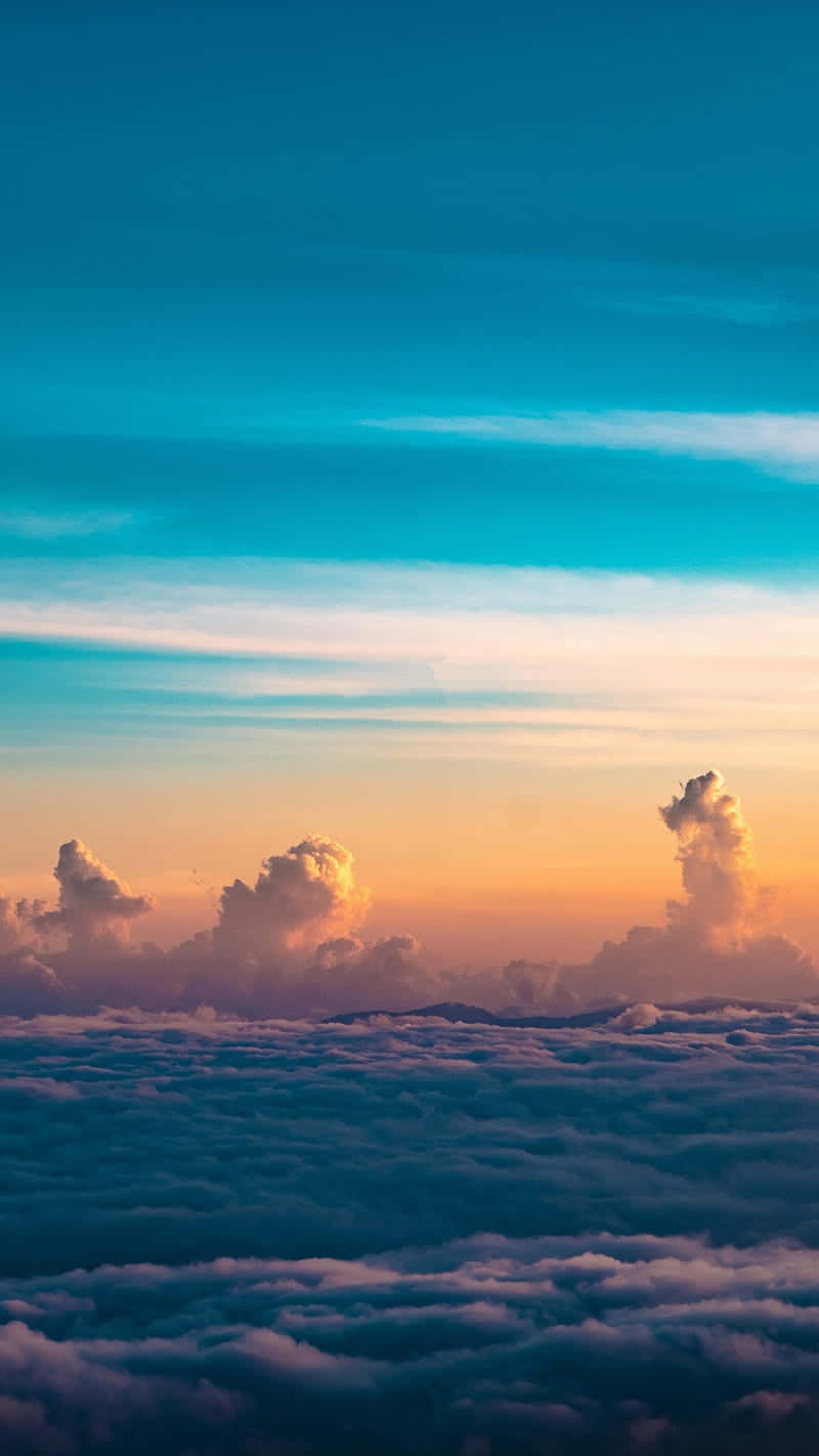 桌布 壁紙 — 日落時分雲海之上的壯麗航拍景色，充滿活力的橙色和藍色天空。
