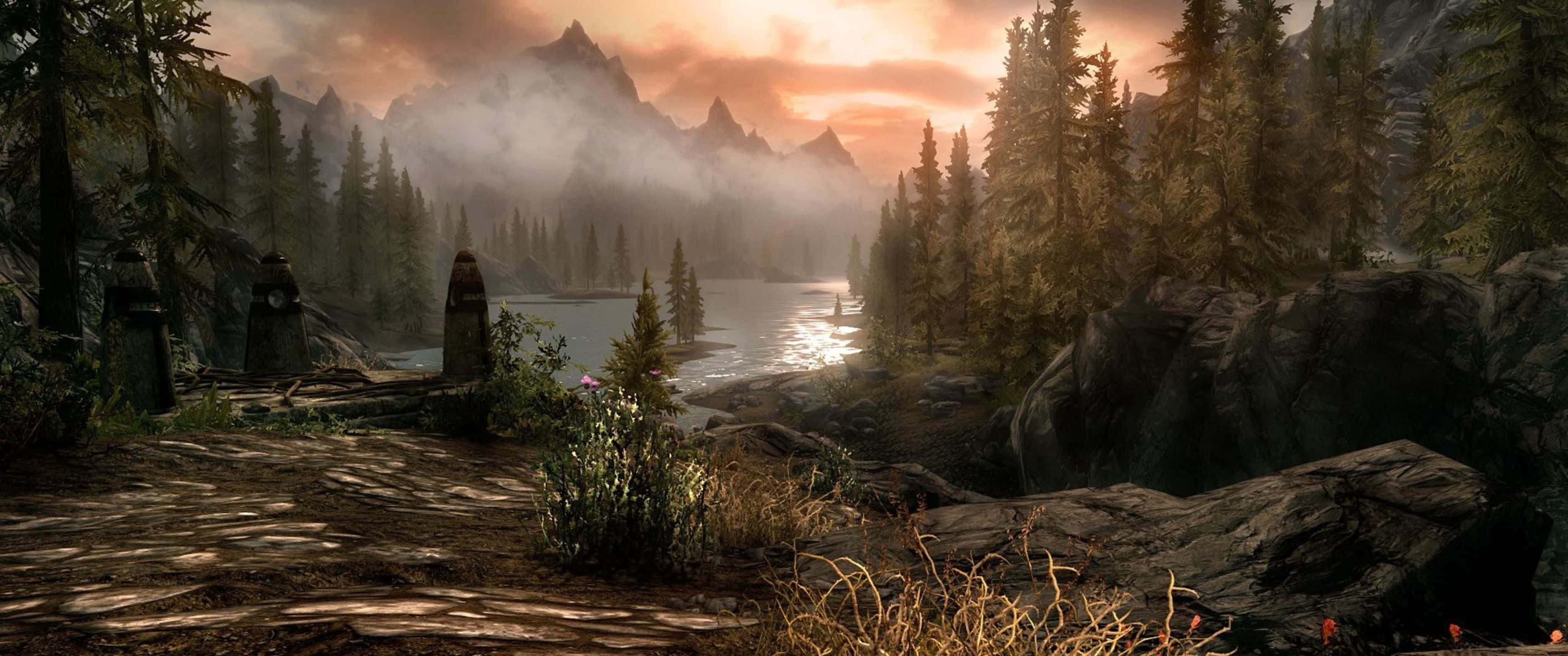 3440x1440p The Elder Scrolls V Skyrim 桌布 壁紙 — 日落時分霧氣繚繞的山間湖泊，高聳的山峰和古老石柱沿著森林小徑排列。