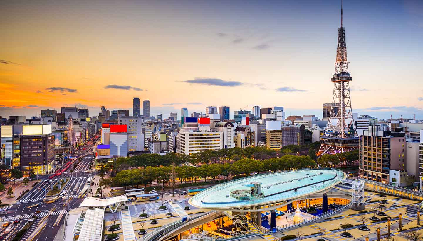 Nagoya 桌布 壁紙 — 日落時東京天際線的鳥瞰圖，東京塔和現代建築在橙色和藍色天空下閃耀。