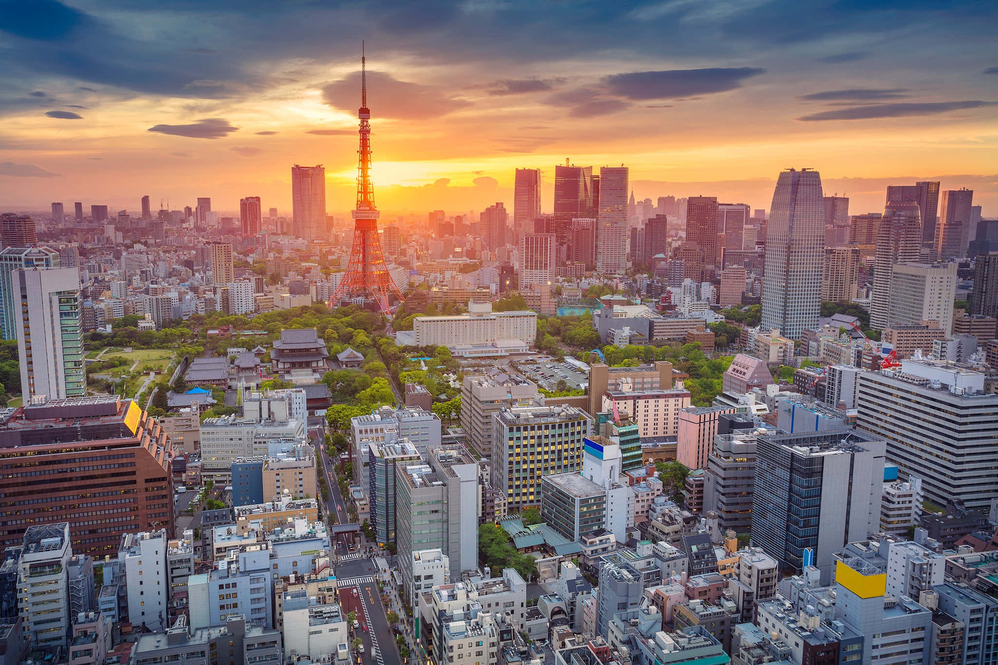 東京 桌布 壁紙 — 日落時東京天際線的鳥瞰圖，東京塔在橙色雲層和密集的城市建築中閃耀。