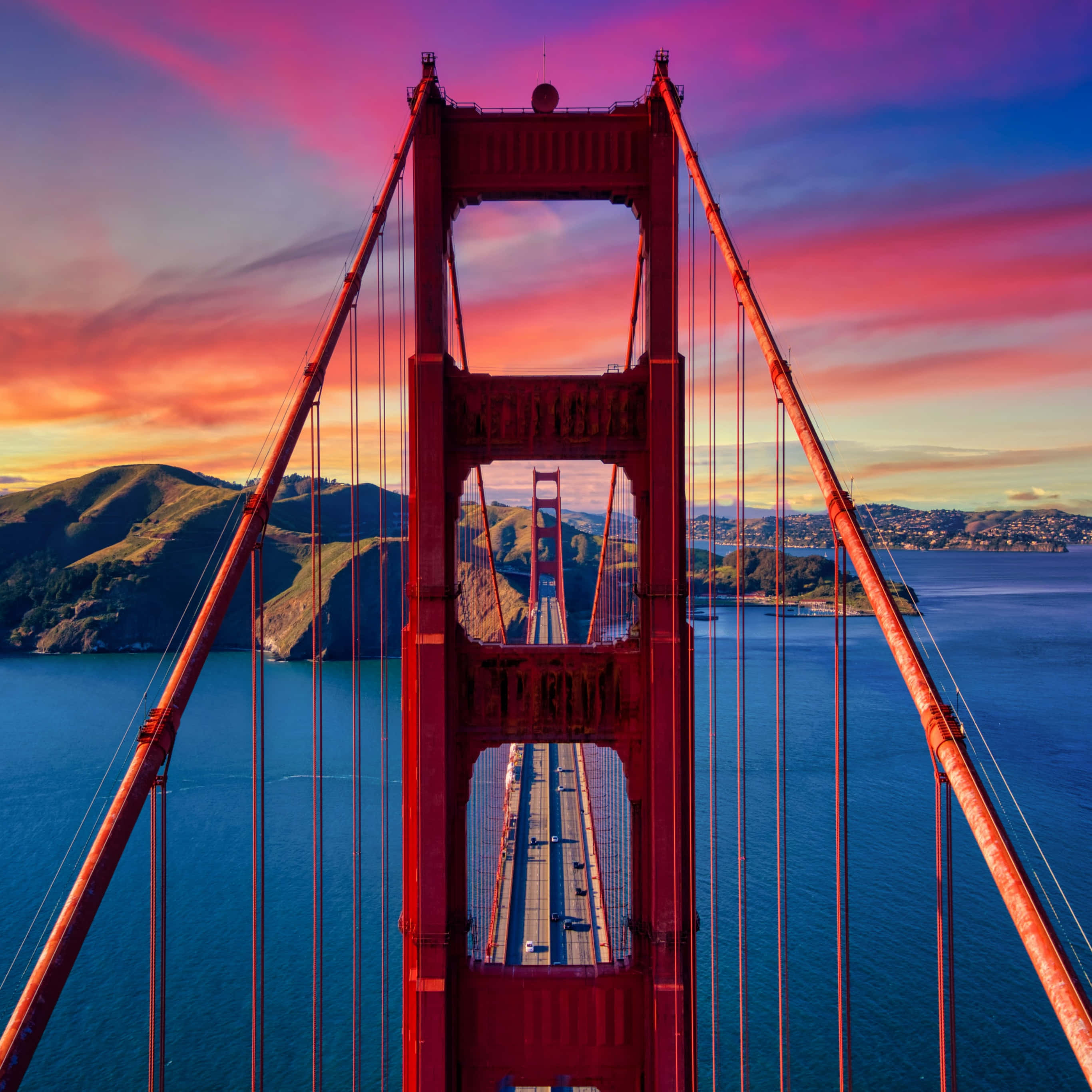 California Aesthetic 桌布 壁紙 — 日落時金門大橋的鳥瞰圖，充滿活力的粉紅色和橙色天空，藍色海水和綠色山丘。