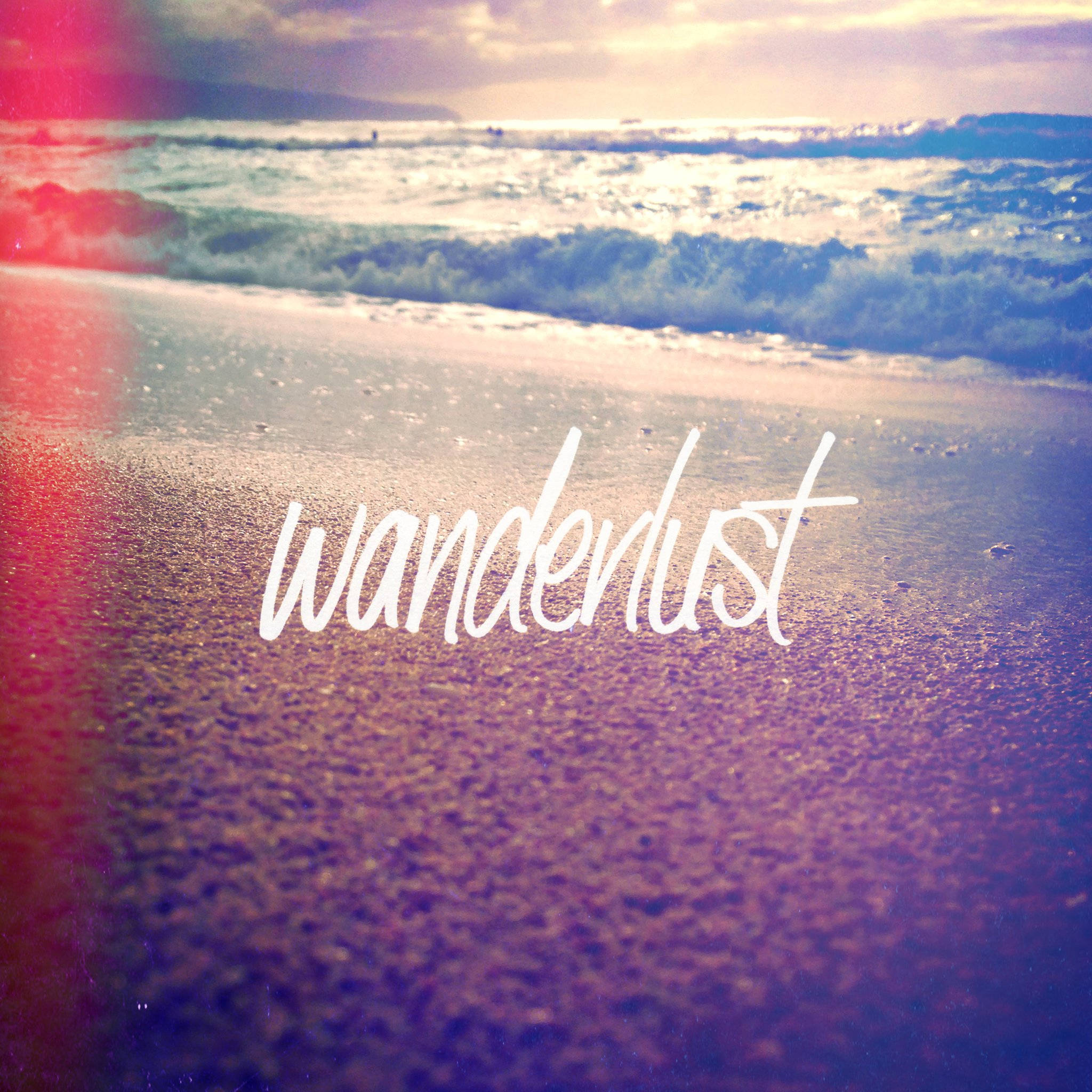 Tumblr 桌布 壁紙 — 日落海灘場景，海浪翻滾，濕沙上用白色字體寫著wanderlust。