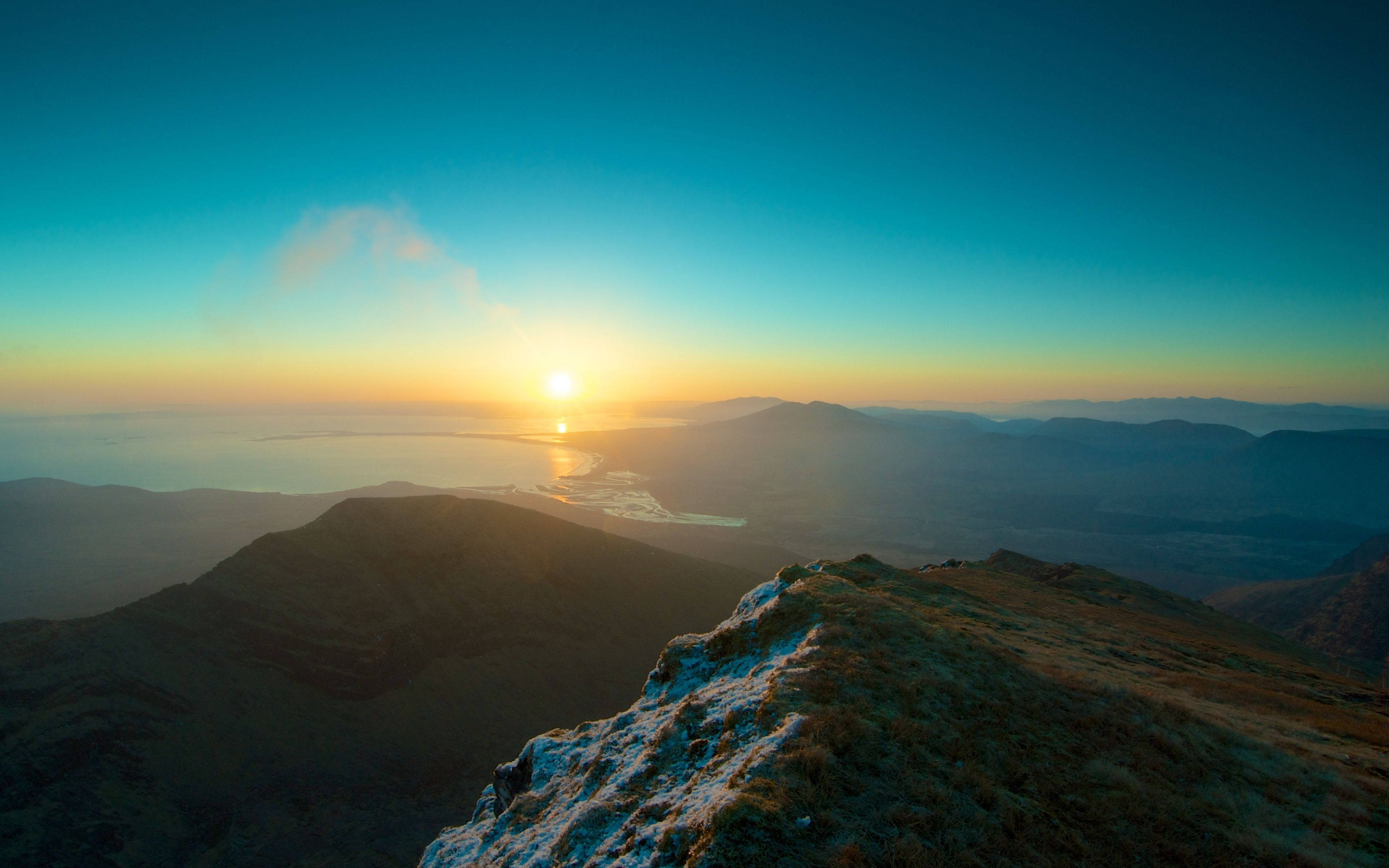 4K 自然 桌布 壁紙 — 日落照亮山脊，遠方山峰和下方平靜的海面。