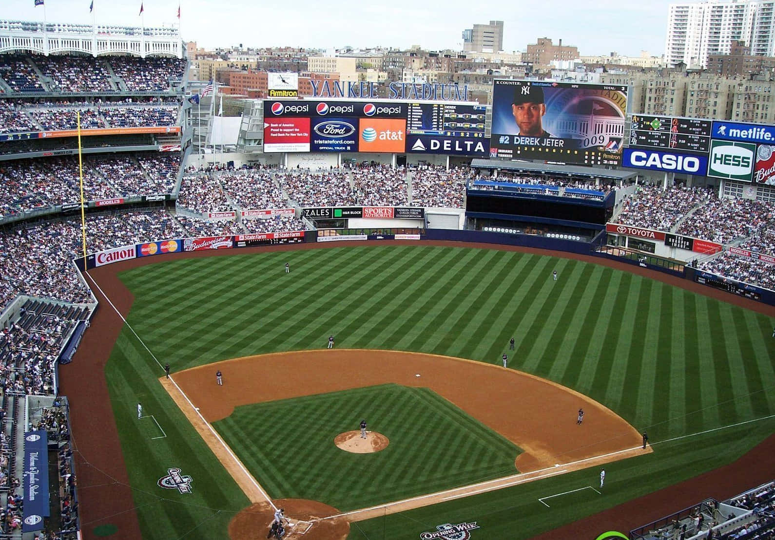 風景 桌布 壁紙 — 日間棒球比賽期間，洋基球場（Yankee Stadium）擠滿球迷，球員在條紋綠色場地上的鳥瞰圖。