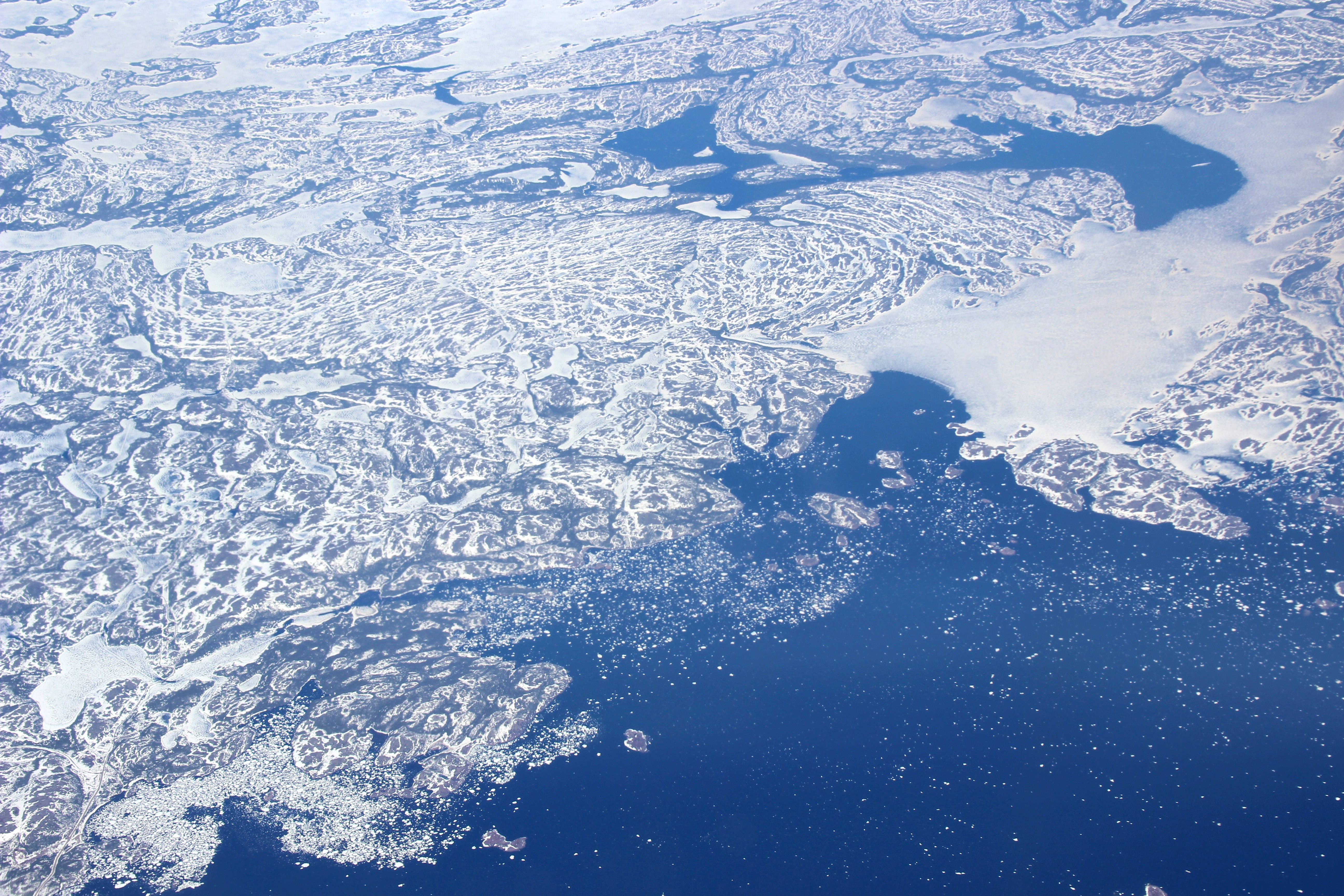 Greenland 桌布 壁紙 — 明亮日光下，破碎海冰在深藍色北極海域漂流的空拍視圖。