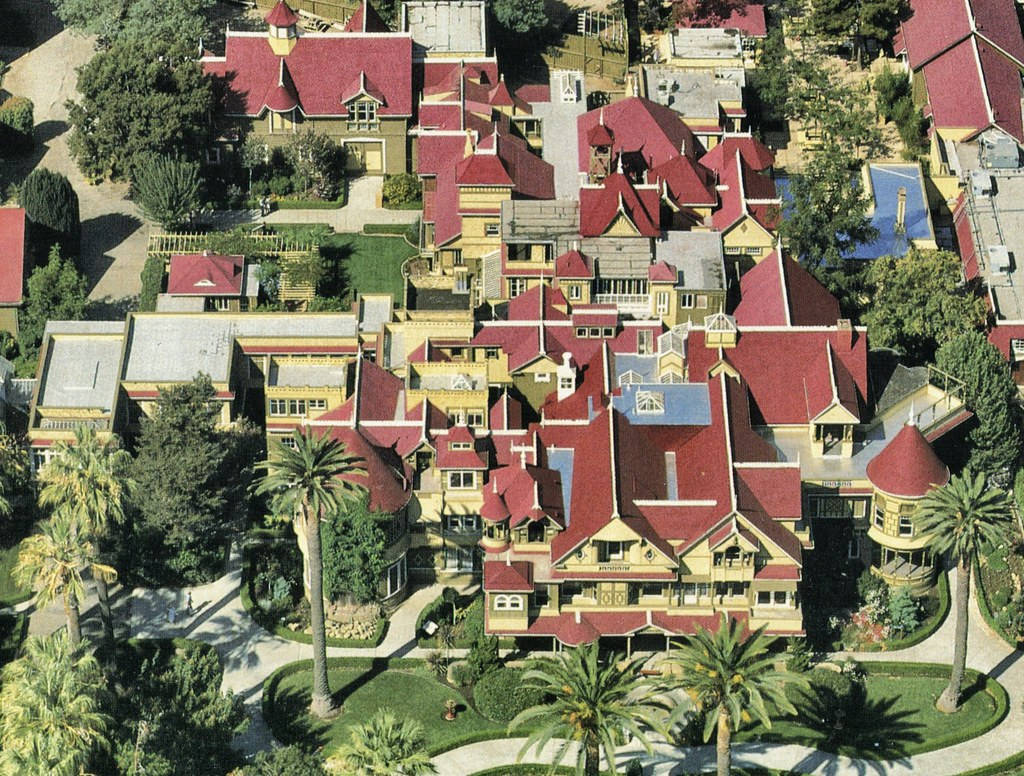 Mansion 桌布 壁紙 — 明亮日光下，紅瓦屋頂和棕櫚樹遍佈的維多利亞風格度假村鳥瞰圖。