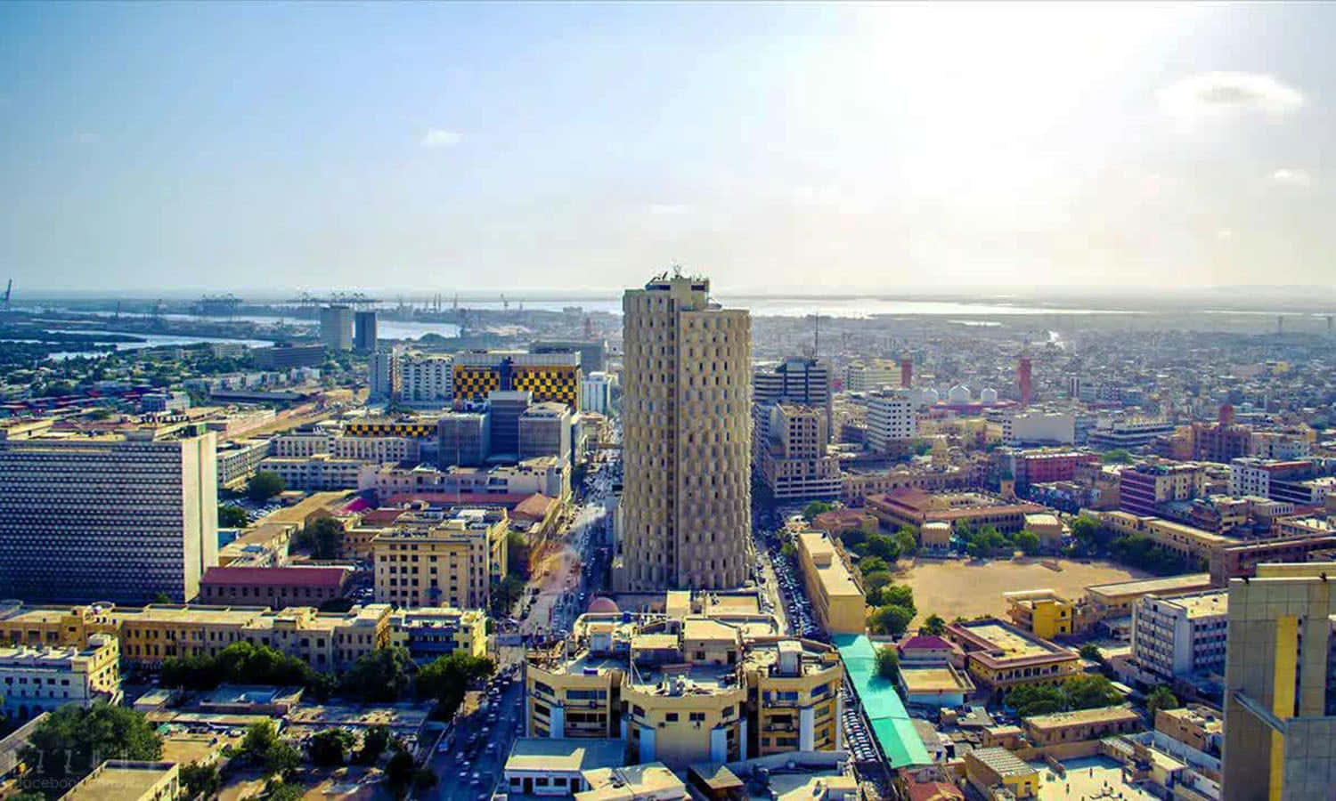 Pakistan 桌布 壁紙 — 明亮日光下，遠方有突出高樓和港口的繁忙城市景觀鳥瞰圖。