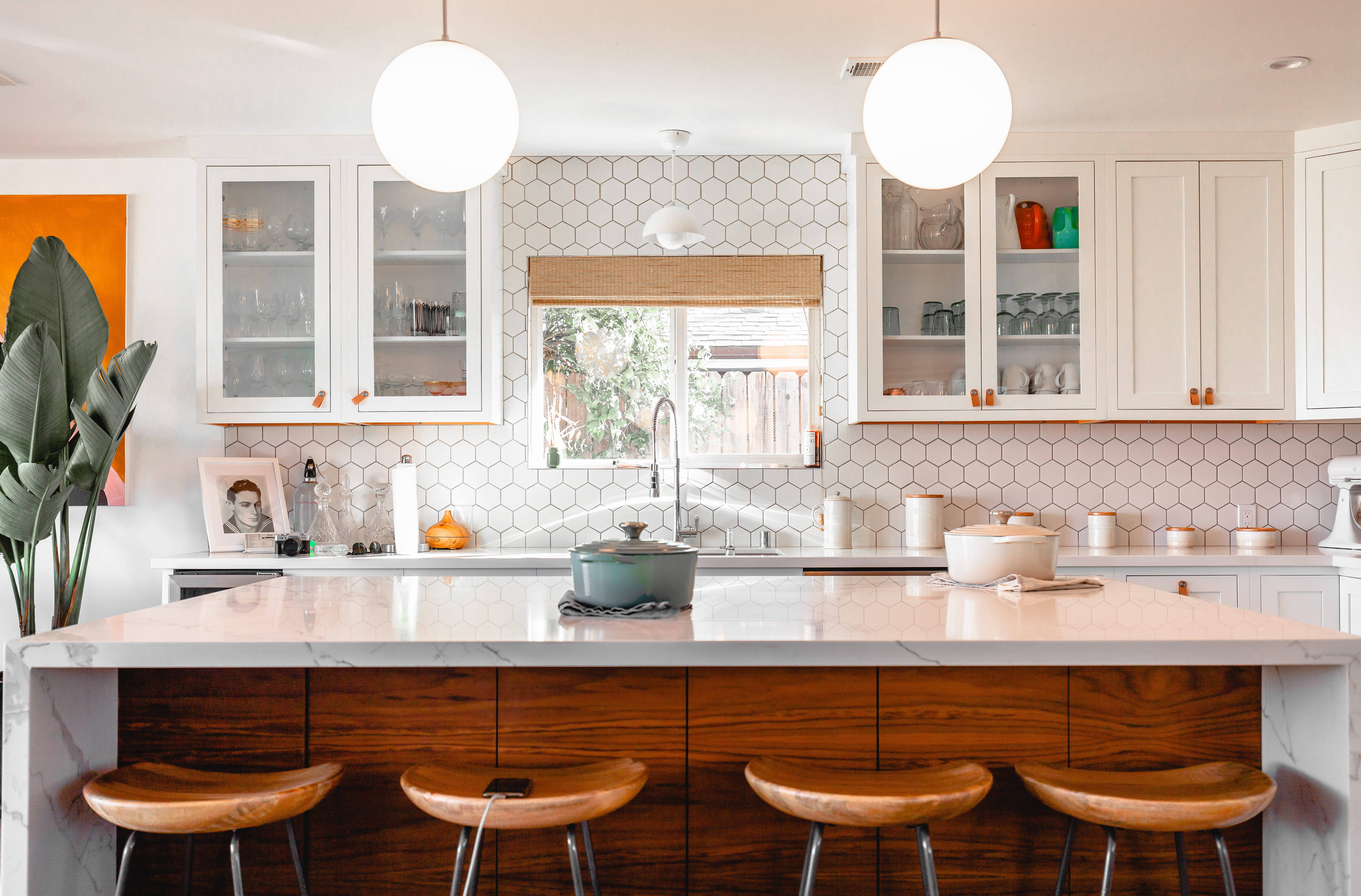 Interior Design 桌布 壁紙 — 明亮現代廚房，配有白色六角形瓷磚防濺板、木製吧檯凳和吊燈。