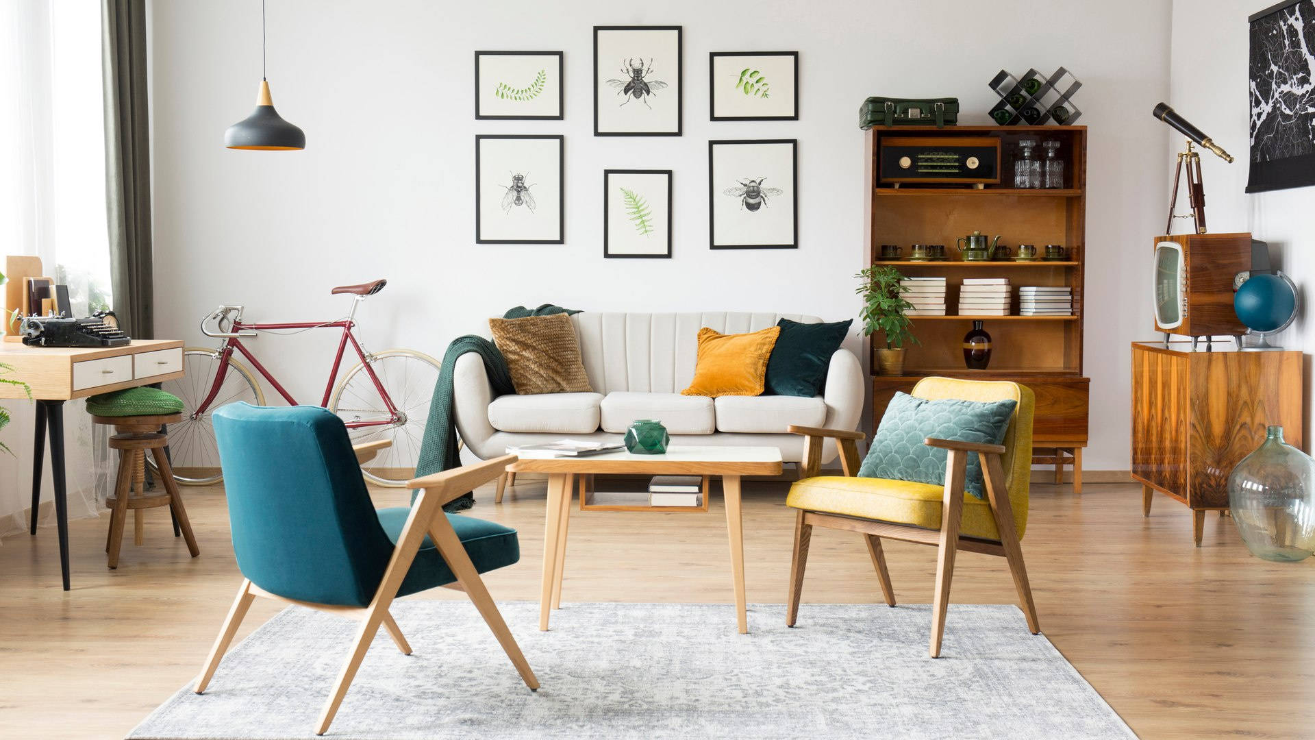 房屋 桌布 壁紙 — 明亮的 mid-century modern 客廳，配有藍綠色和黃色椅子、木製家具，以及白色牆上裱框的昆蟲藝術品。