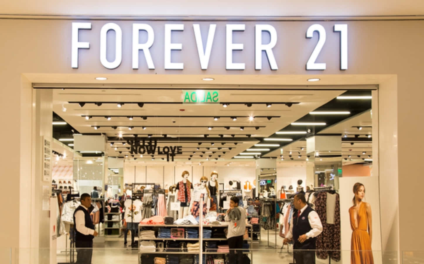 永遠21 桌布 壁紙 — 明亮的Forever 21商店入口，顯示購物者在發光招牌下瀏覽衣架和模特兒。