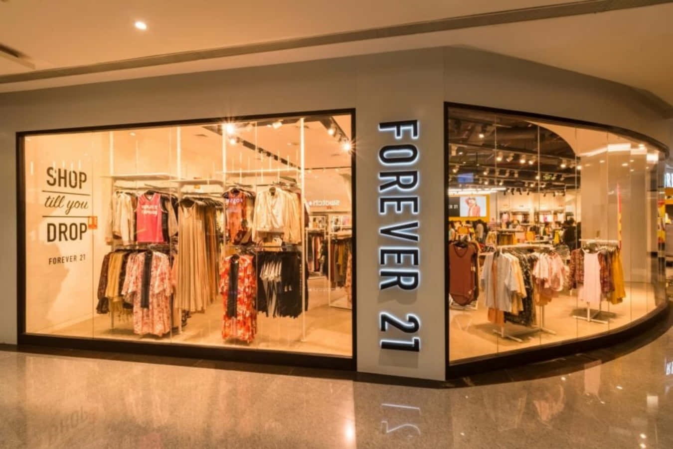 永遠21 桌布 壁紙 — 明亮的Forever 21店面，玻璃窗展示色彩繽紛的衣架和發光招牌。