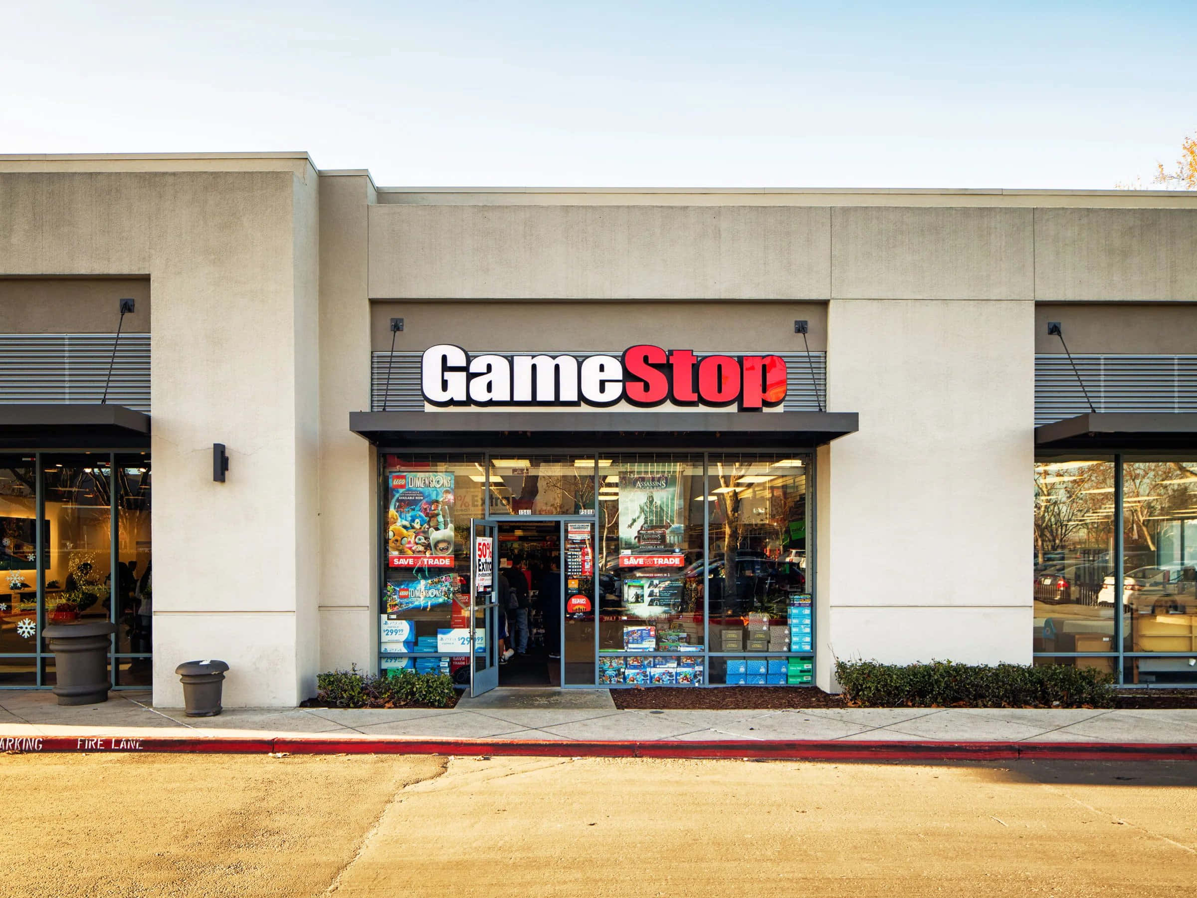 GameStop 桌布 壁紙 — 明亮的GameStop店面，玻璃窗展示電玩遊戲和商品，天空晴朗。
