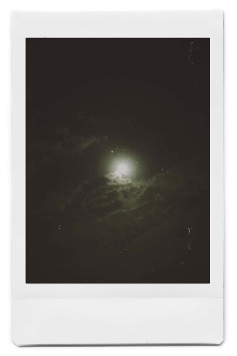 Aesthetic Polaroid 桌布 壁紙 — 明亮的月亮穿過烏雲照耀，在一個帶有可見刮痕和顆粒的復古拍立得相框中。