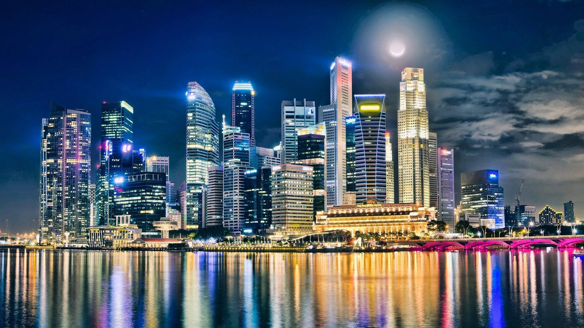 明尼蘇達 桌布 壁紙 — 明亮的月光下，高聳的摩天大樓在平靜的水面上反射出鮮豔燈光的迷人夜景。