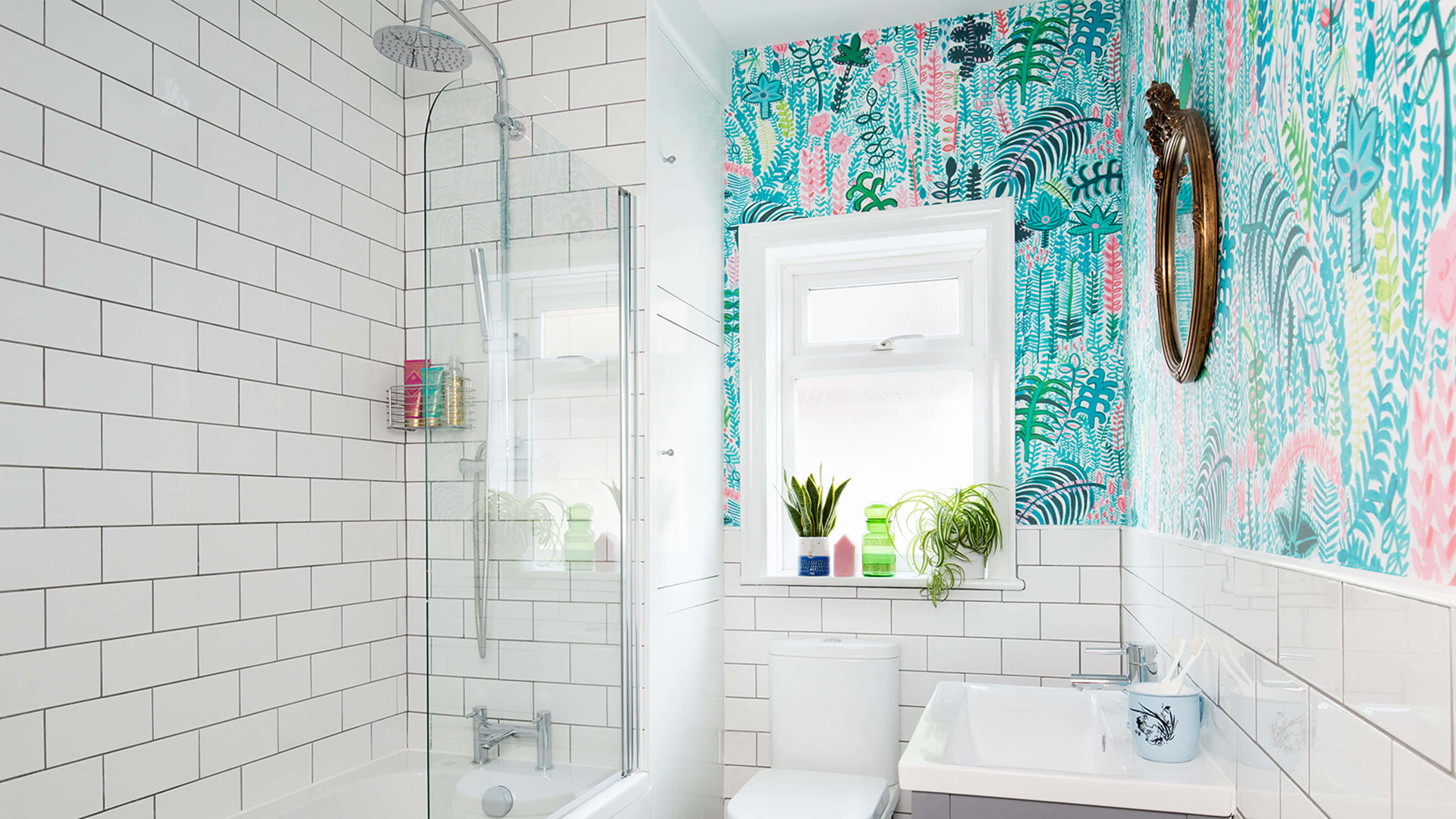 Bathroom Decor 桌布 壁紙 — 明亮的浴室，配有白色地鐵磚和充滿活力的熱帶壁紙特色牆，設有帶盆栽植物的窗戶。