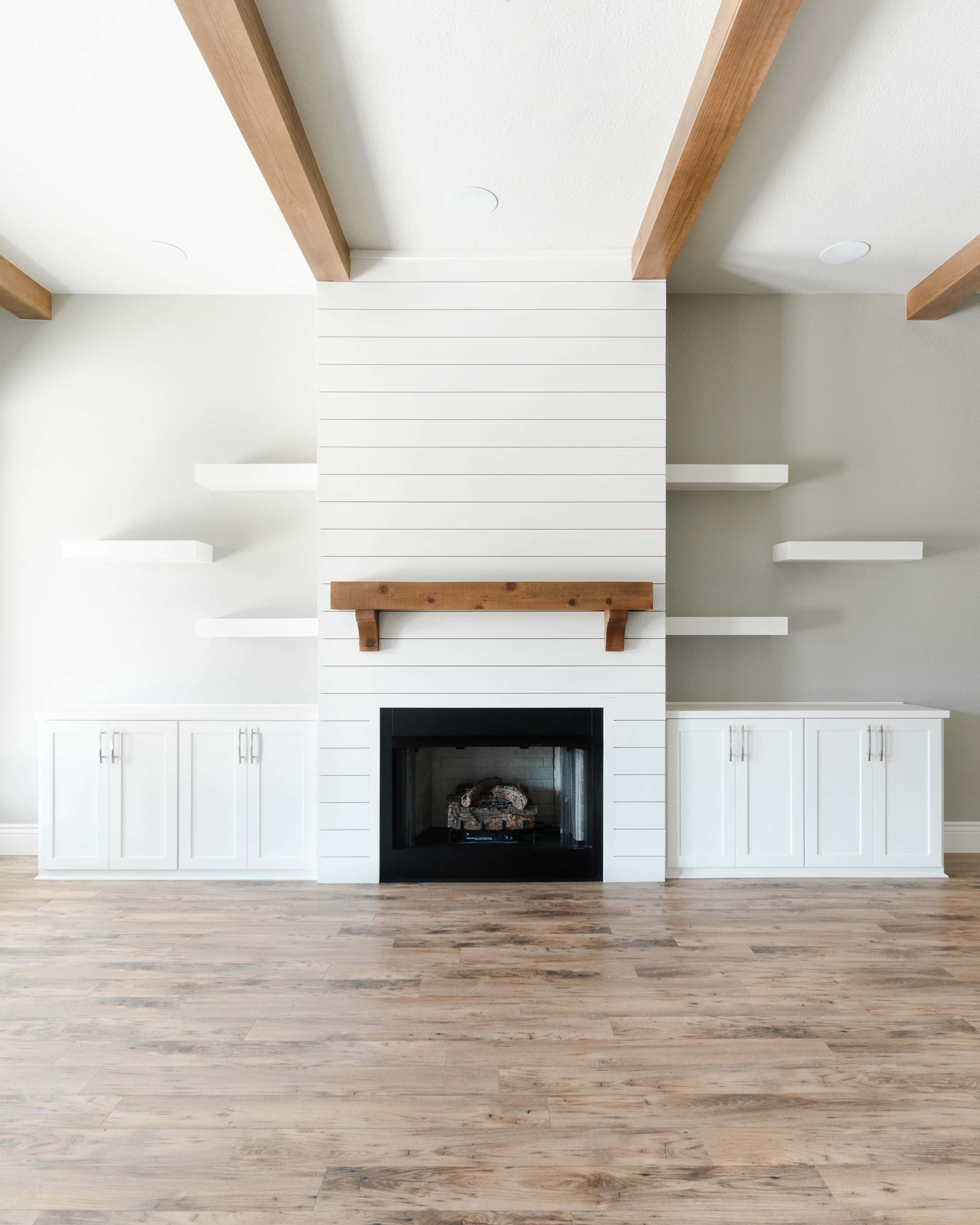 Shiplap 桌布 壁紙 — 明亮的現代客廳設有白色木條壁爐，搭配木樑和浮動層架，襯托淺色牆壁。