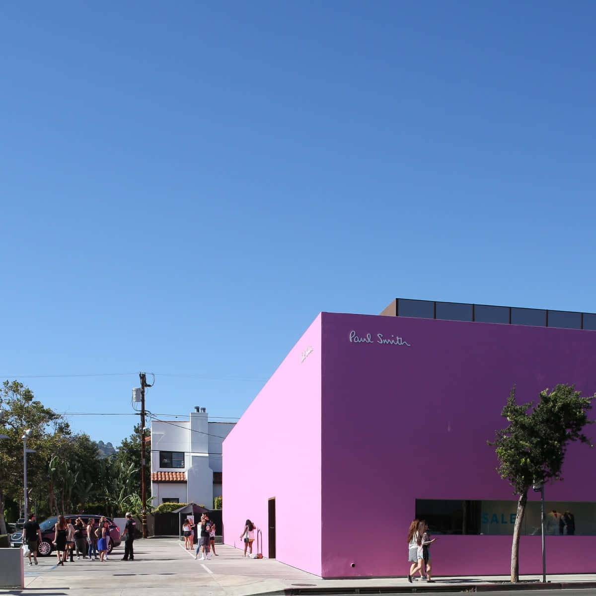 Pink Wall 桌布 壁紙 — 明亮的粉紅色 Paul Smith 商店建築，在清澈的藍天下，行人走在人行道上。
