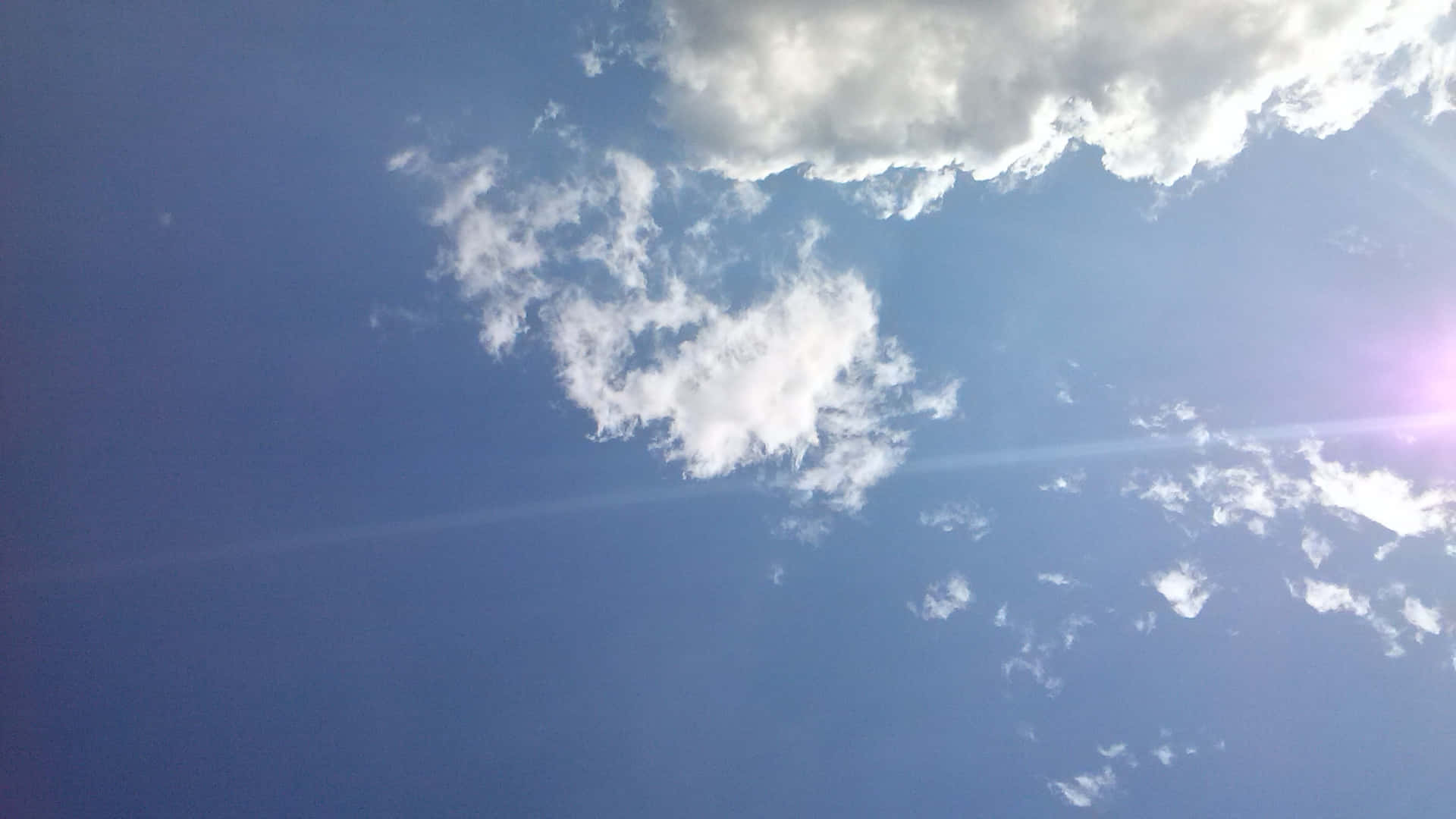 SKY-24 壁紙 — 明亮的藍天， fluffy 白雲，角落有太陽耀斑。