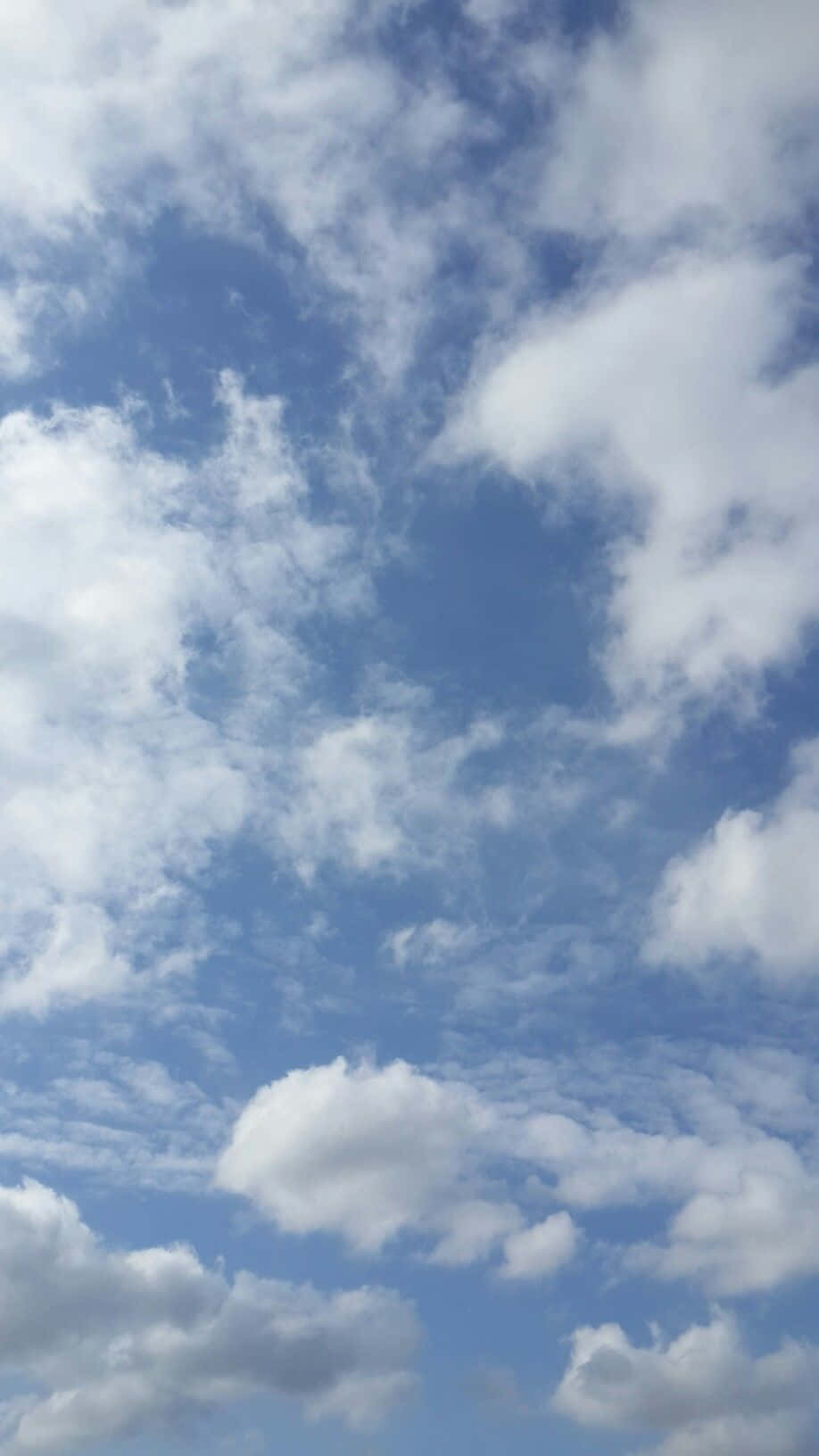 Blue Sky Aesthetic 桌布 壁紙 — 明亮的藍天，充滿蓬鬆的白雲，飄過地平線。
