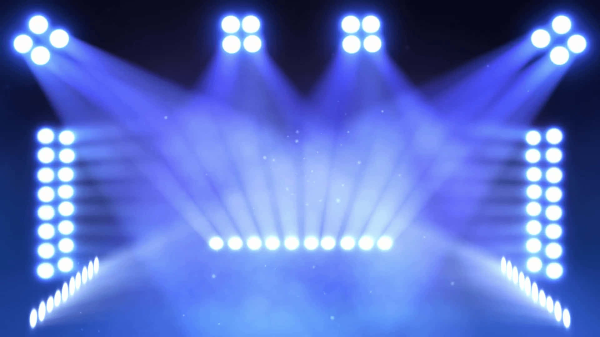 Stage Lights 桌布 壁紙 — 明亮的藍色舞台燈光從上方和側面照射下來，在黑暗的場地中營造出戲劇性的聚光燈效果。