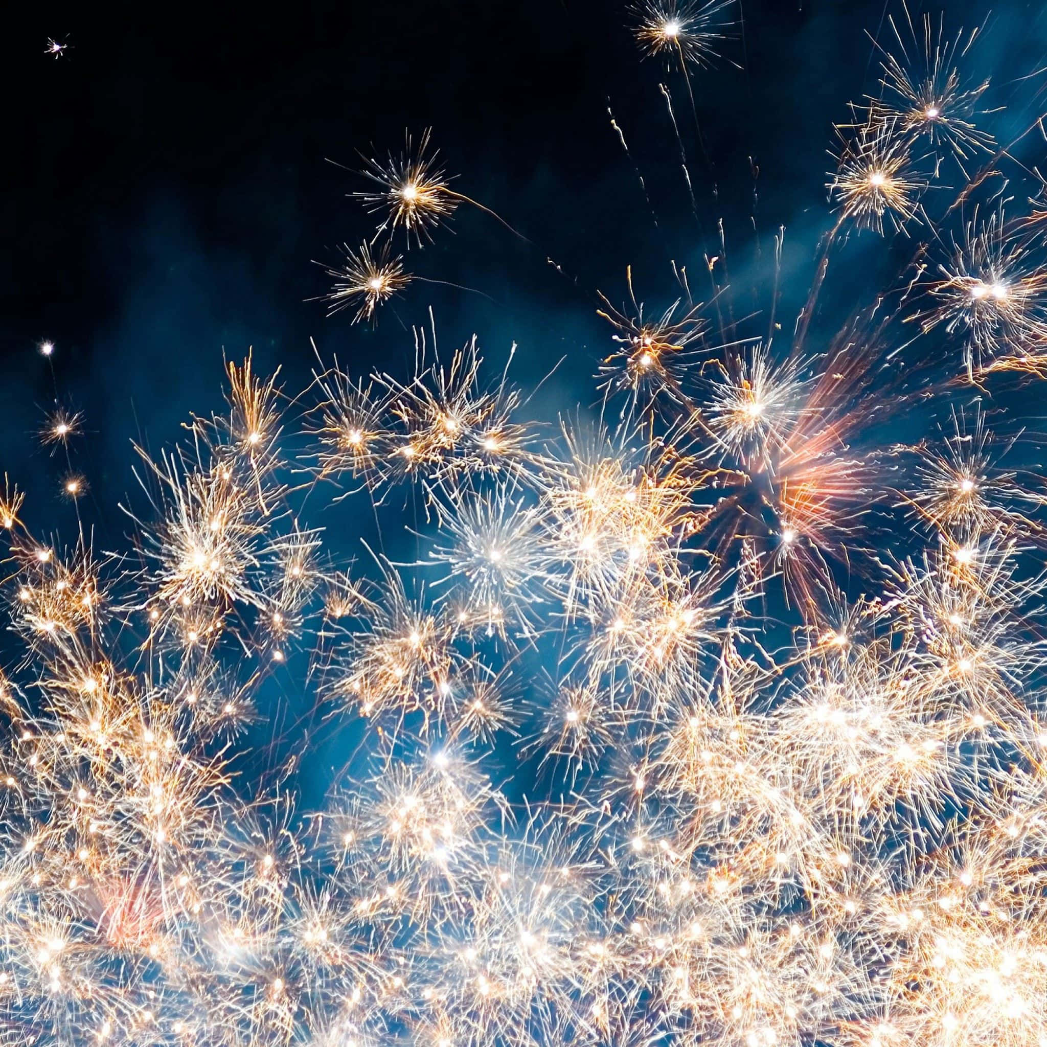 Fireworks 桌布 壁紙 — 明亮的金色煙火在深藍色夜空中爆炸，形成耀眼的星爆圖案。