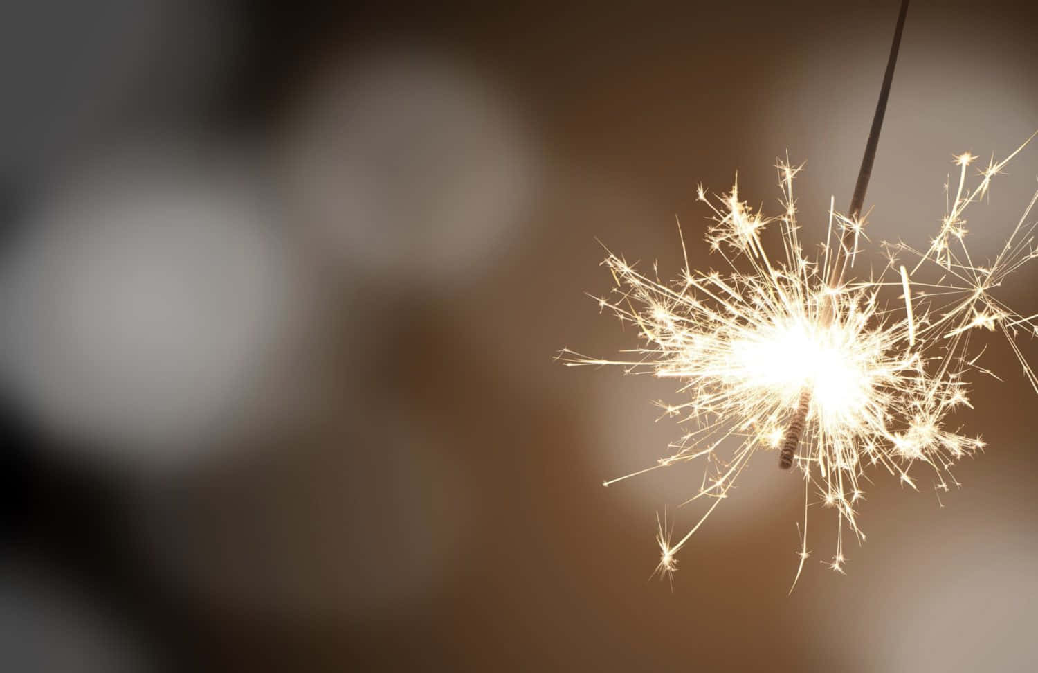 新年 桌布 壁紙 — 明亮的閃爍煙火在柔和模糊的背景上爆發出金色光芒。