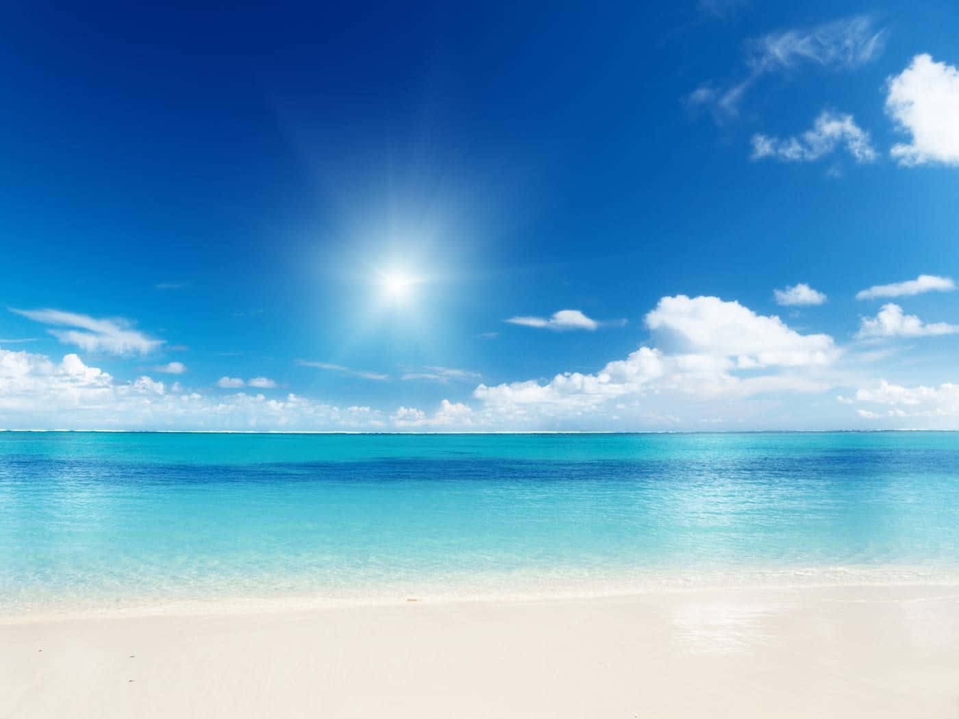 Caribbean Beach 桌布 壁紙 — 明亮的陽光照耀在碧綠的海水上，與白色沙灘相接，天空湛藍，白雲點綴。