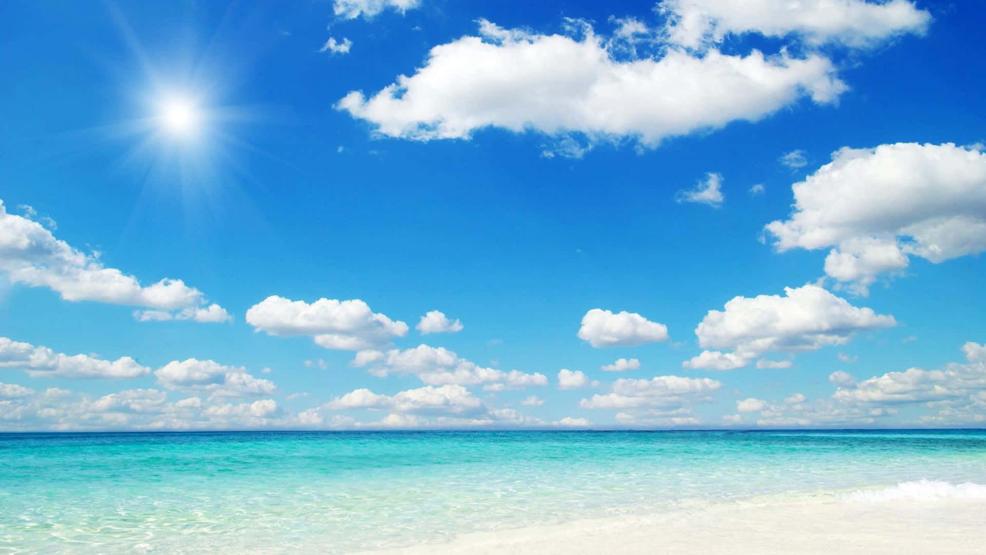 Beautiful Sky 桌布 壁紙 — 明亮的陽光照耀在碧綠的海水與白色沙灘交會處，上方是生動的藍天和蓬鬆的白雲。
