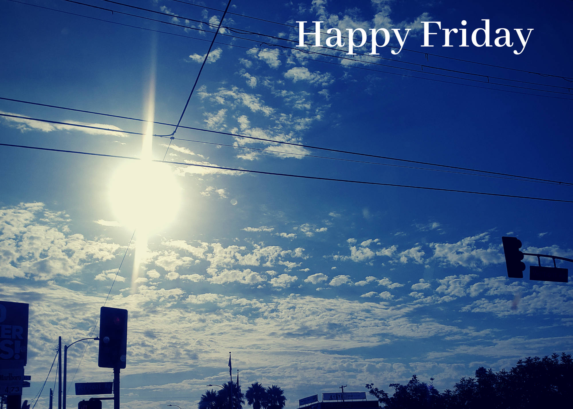 Friday 桌布 壁紙 — 明亮的陽光穿過散落的雲層，照耀在城市街道標誌和交通燈之上。
